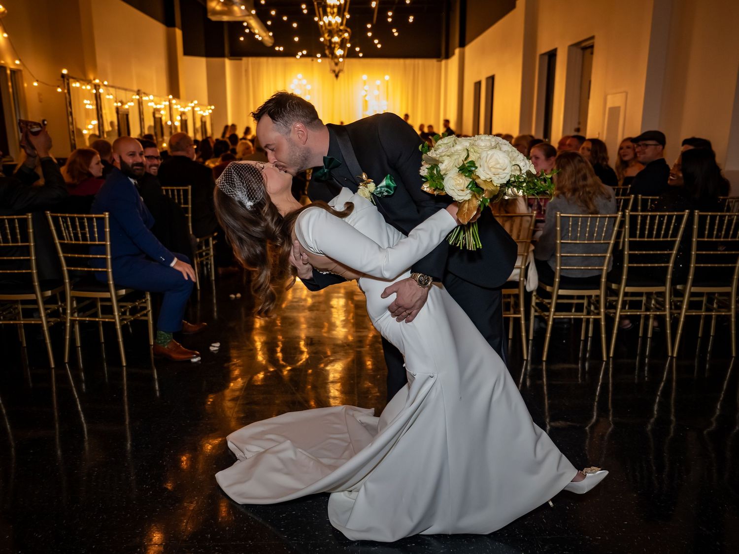 Wedding reception dance floor with guests celebrating under warm string lights.