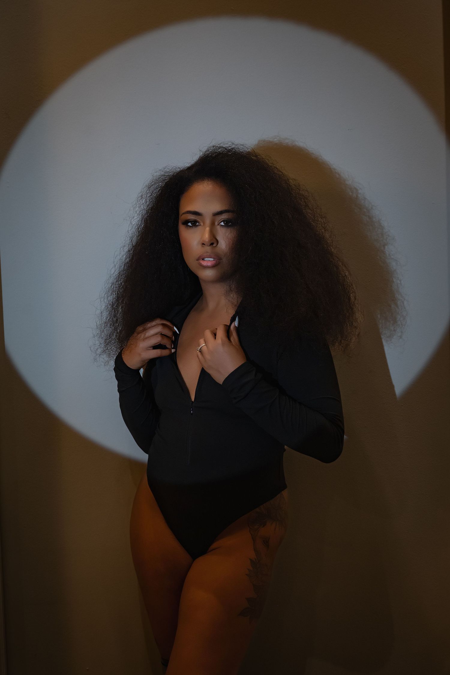 Artistic portrait with dramatic spotlight effect against dark background.