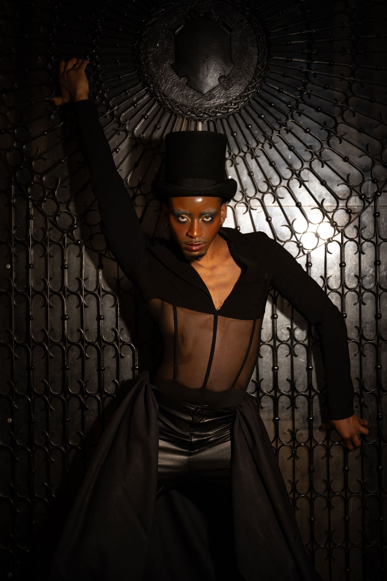 Artistic portrait with dramatic lighting showing dancer in black costume against textured wall.
