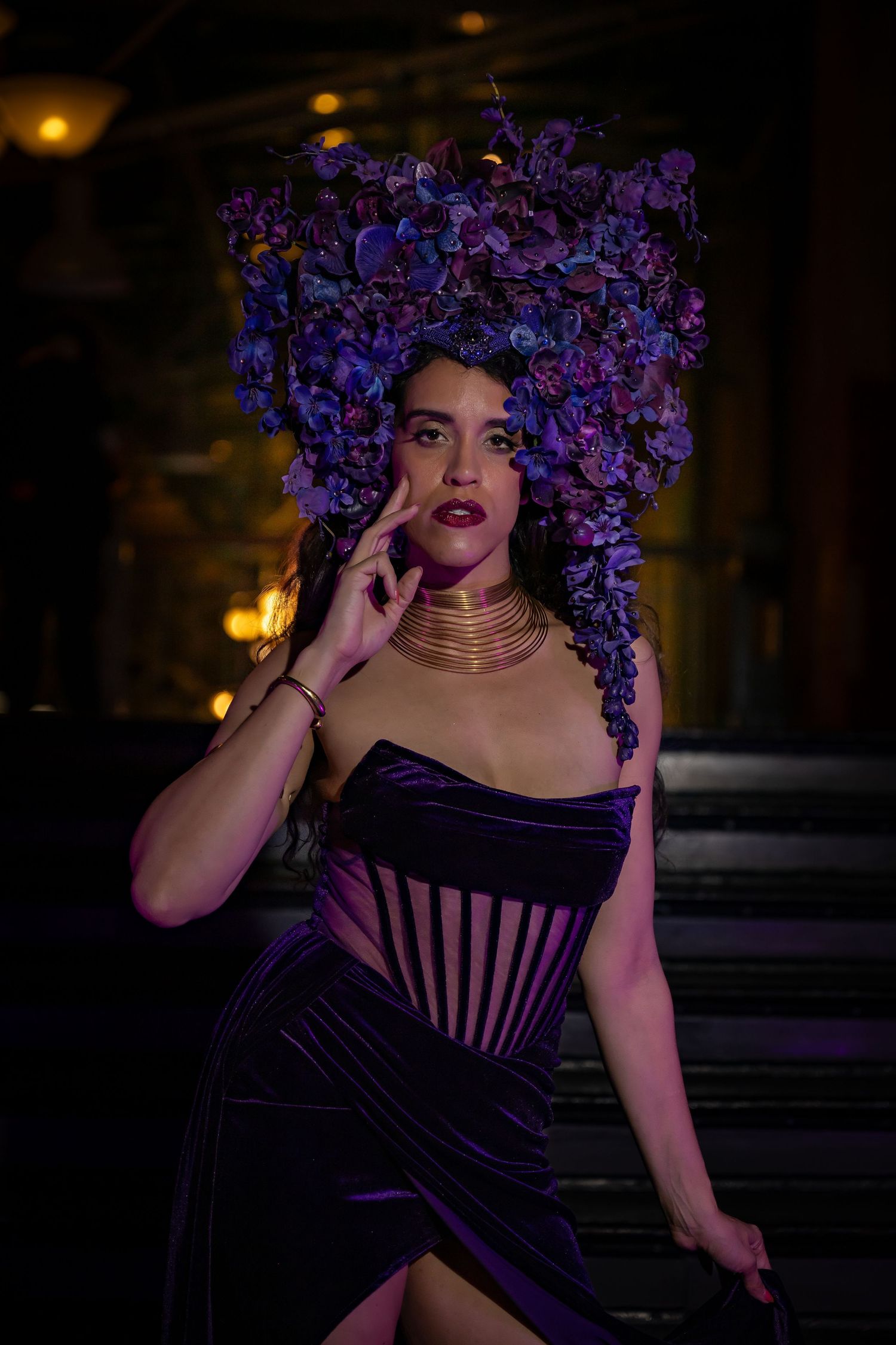 Dramatic portrait with purple floral headpiece against dark background with moody lighting.