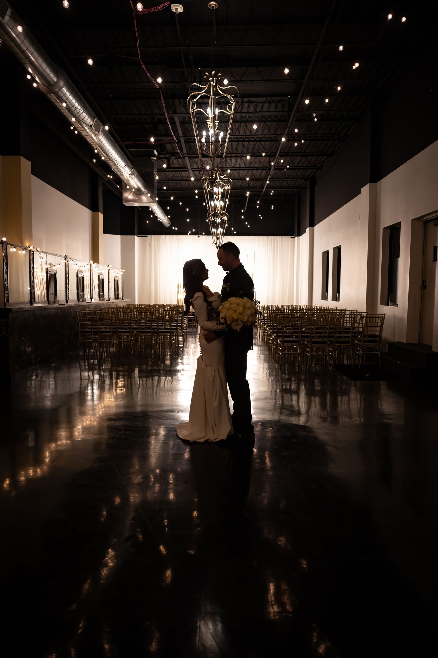 Silhouetted figures dance in dimly lit ballroom with dramatic lighting.