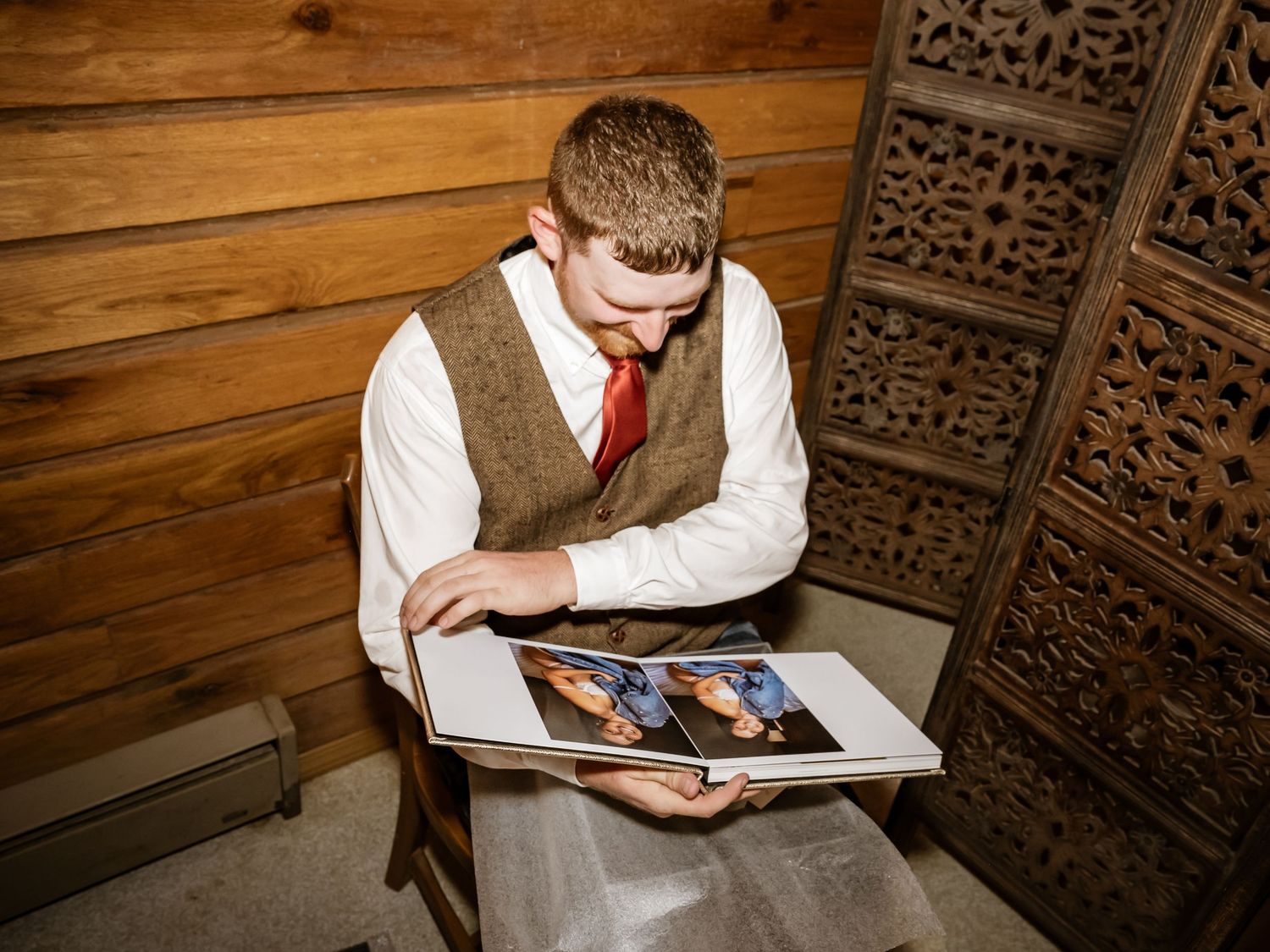 Wedding guests sign guestbook at rustic wooden table with decorative carved panels.