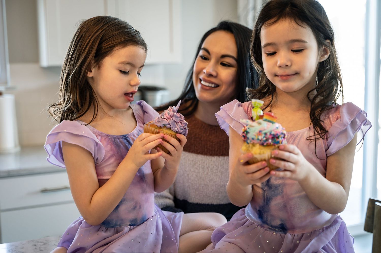 Family enjoying cupcakes together in a cozy indoor setting with natural light.