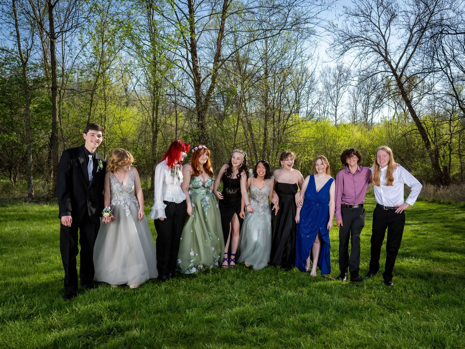 Large wedding party group photo in a spring outdoor setting with blooming trees.