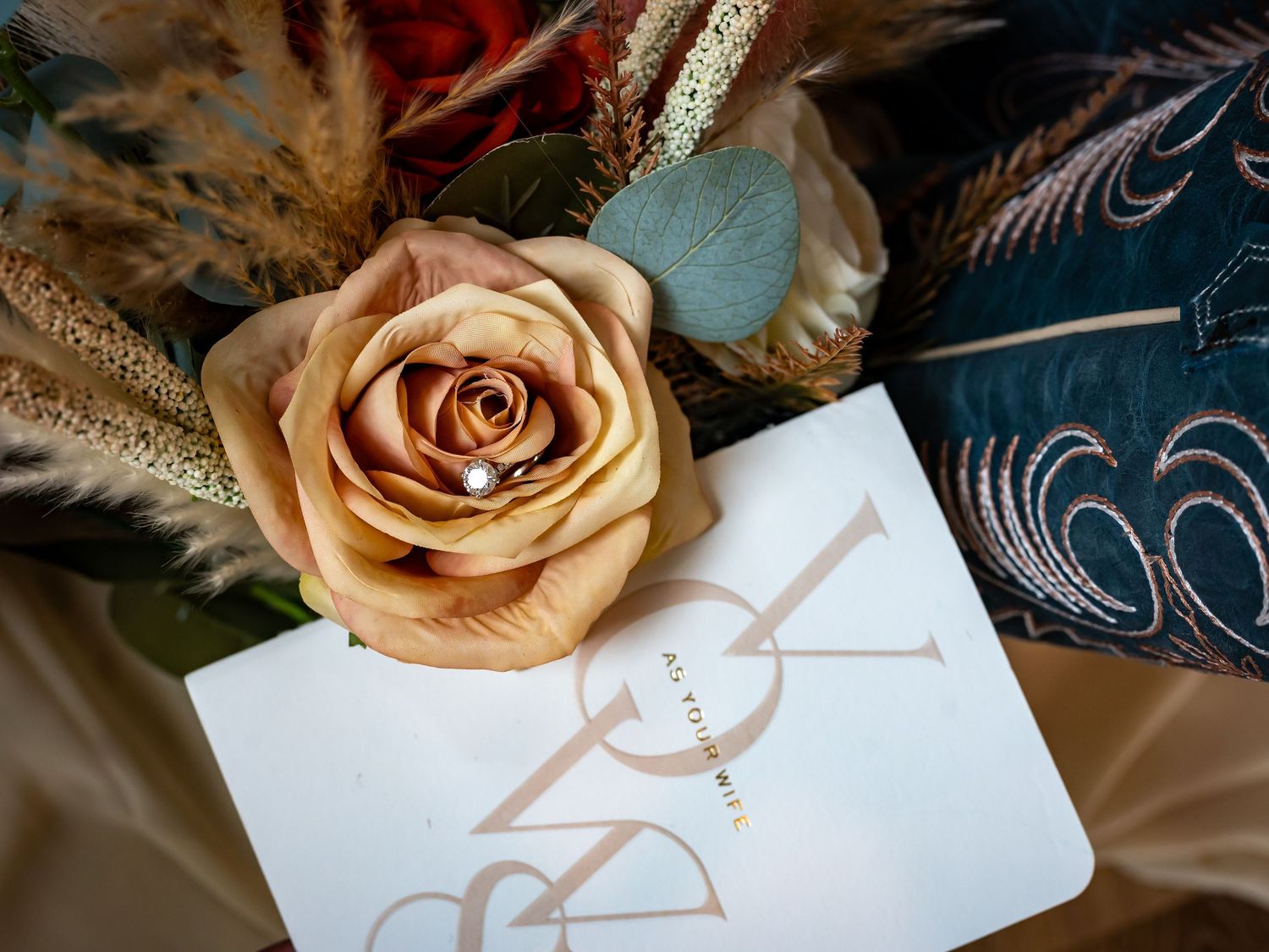Peach rose and wedding stationery details arranged artistically.
