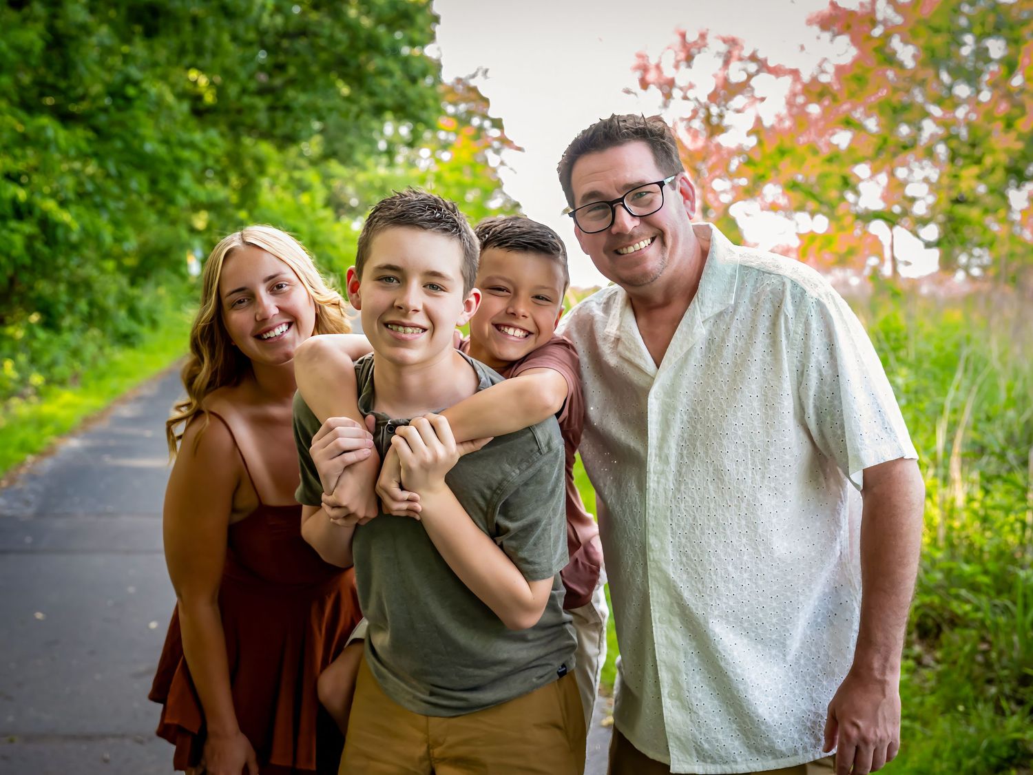A playful outdoor family photo session among lush green trees and foliage.