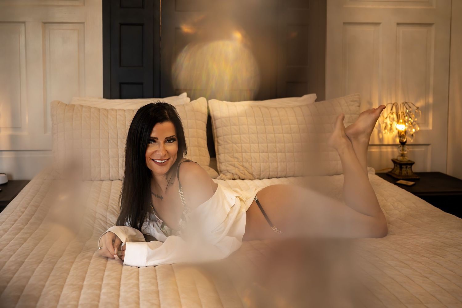 A cozy bedroom interior with white bedding, exposed brick walls, and warm lighting creates an inviting atmosphere.