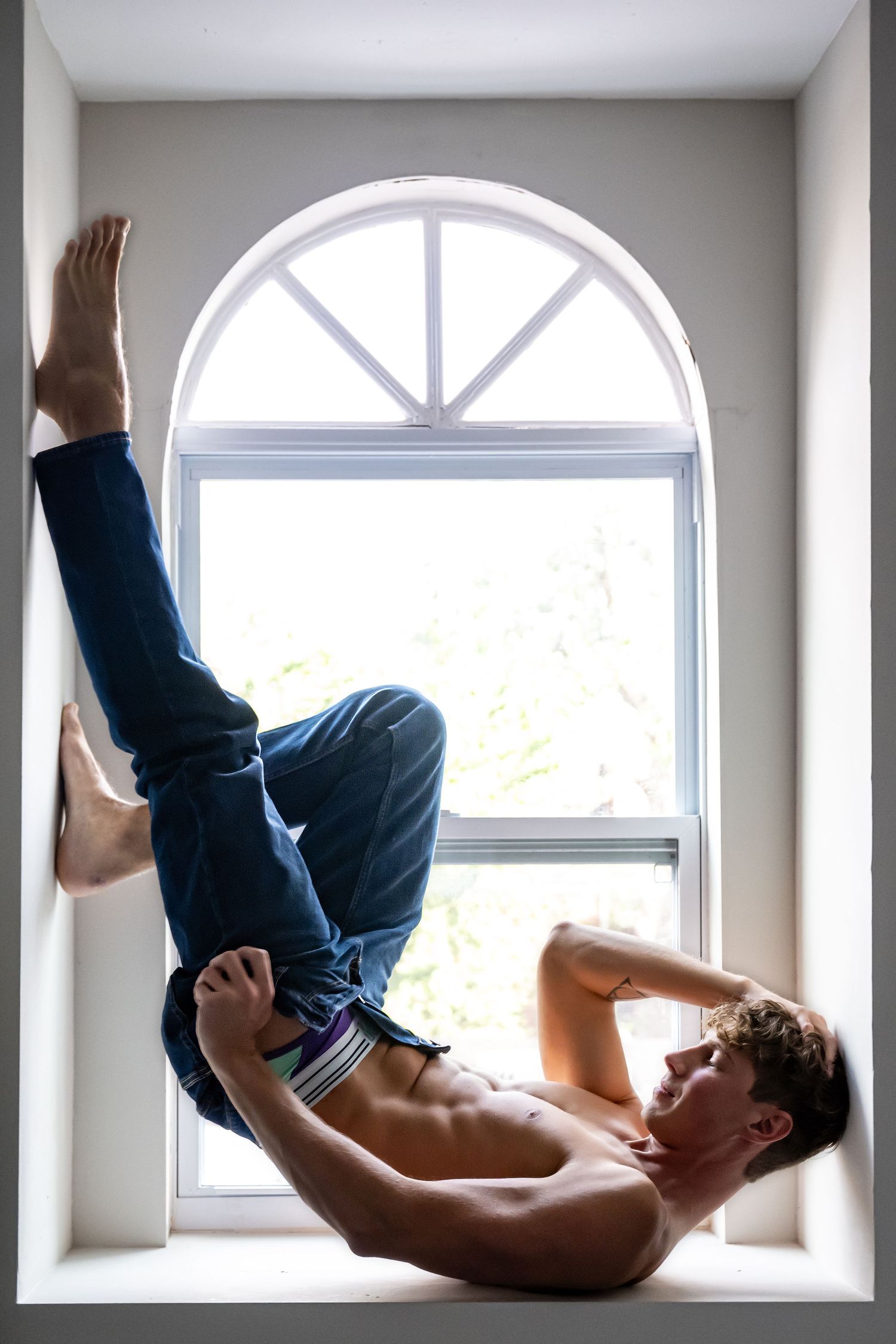 A sequence of five photos showing a shirtless person performing a rolling movement across a window ledge in an indoor space.