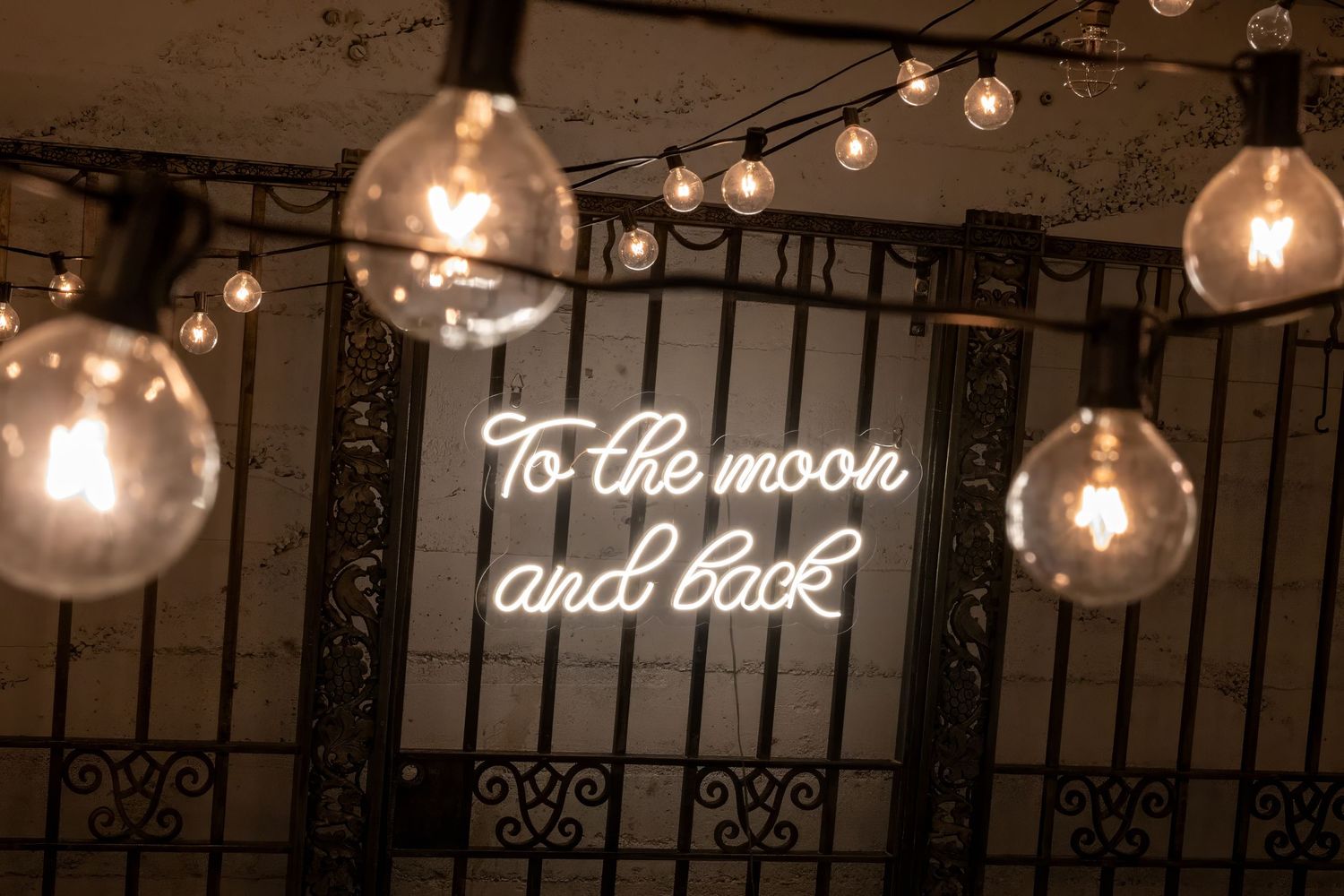 Vintage Edison bulb lighting with neon text sign reading 'To the moon'.