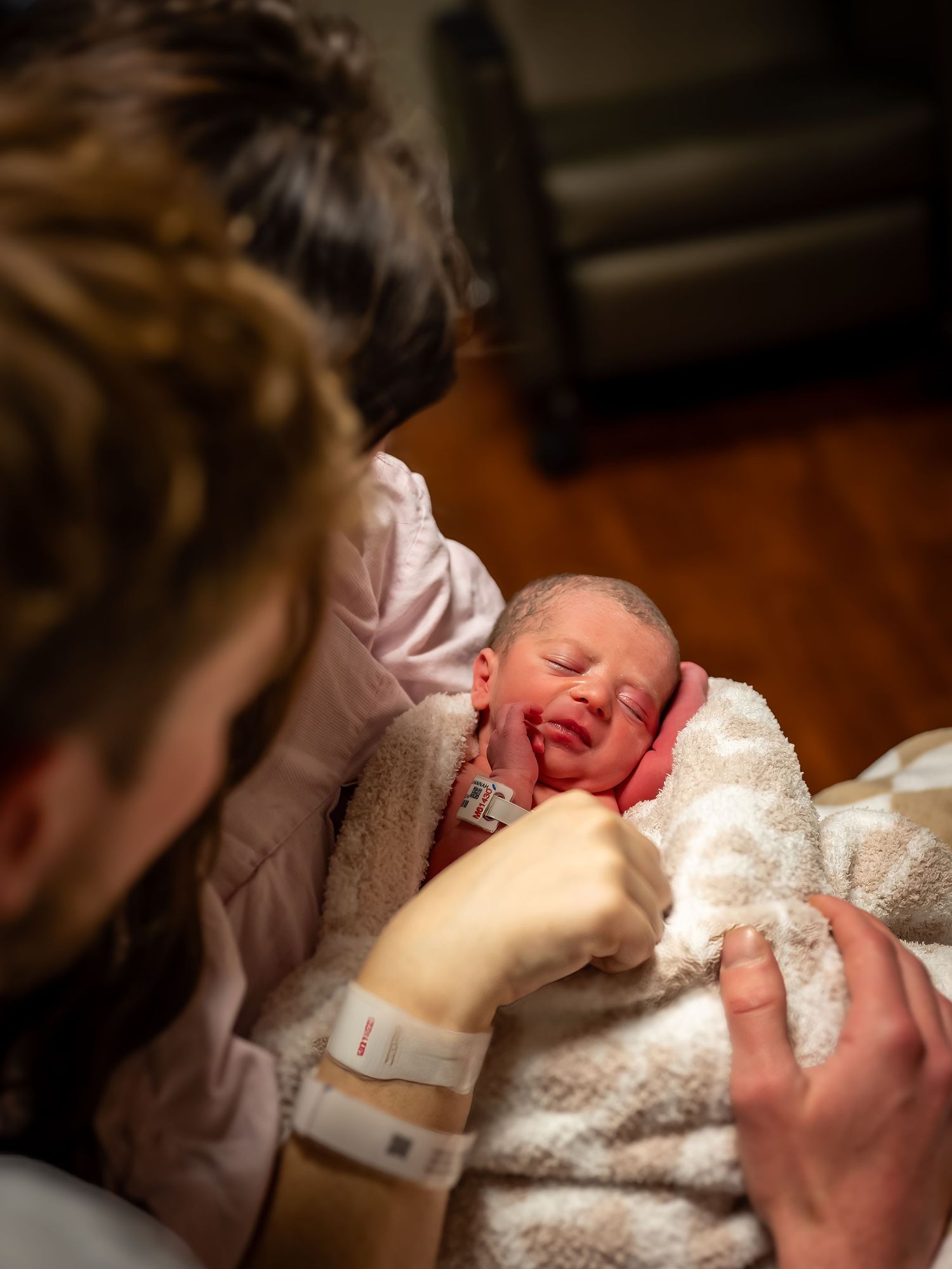Newborn baby wrapped in white blanket during first moments.