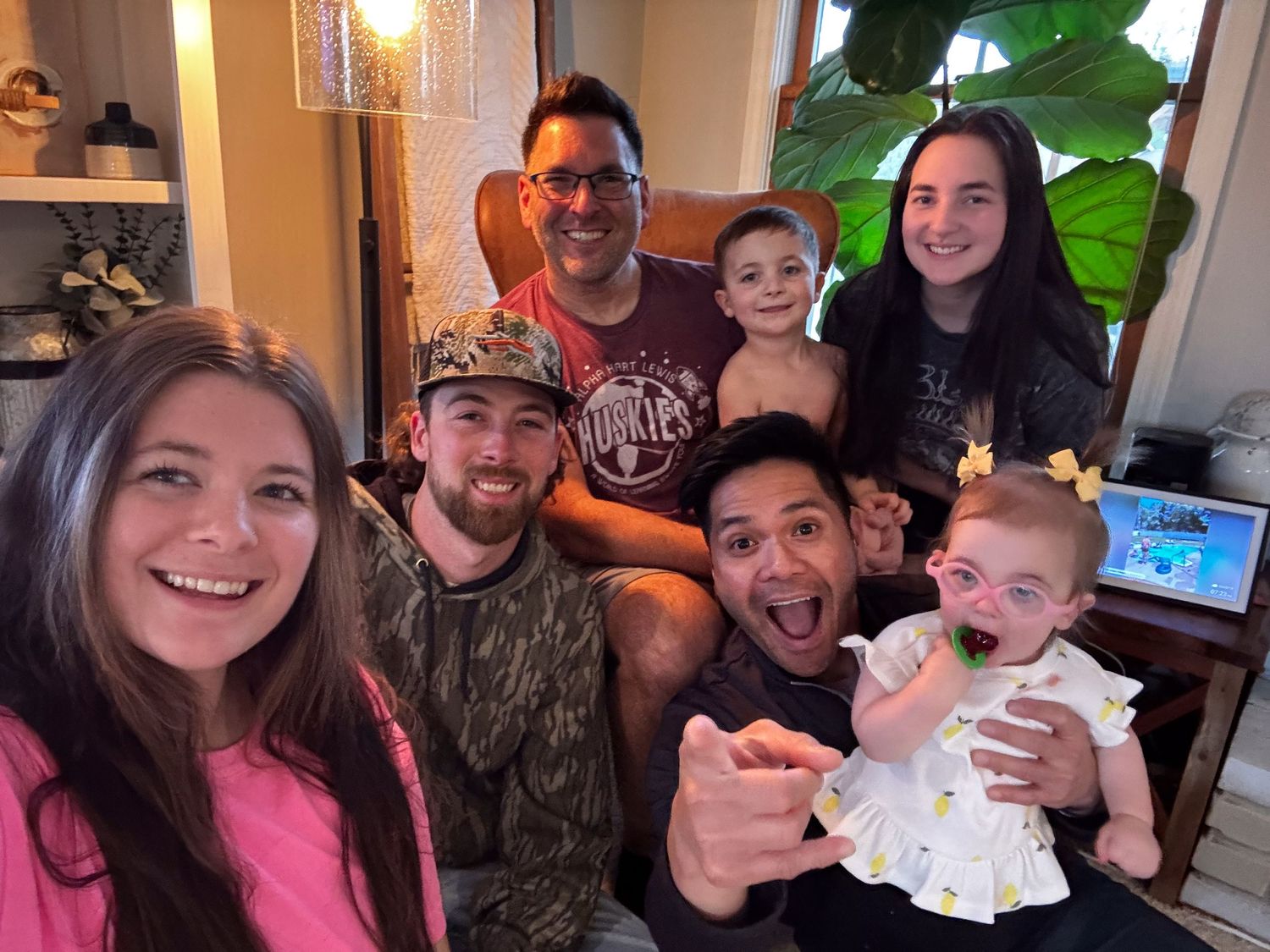 A group of people sit together on a couch smiling and enjoying time together in a living room setting.