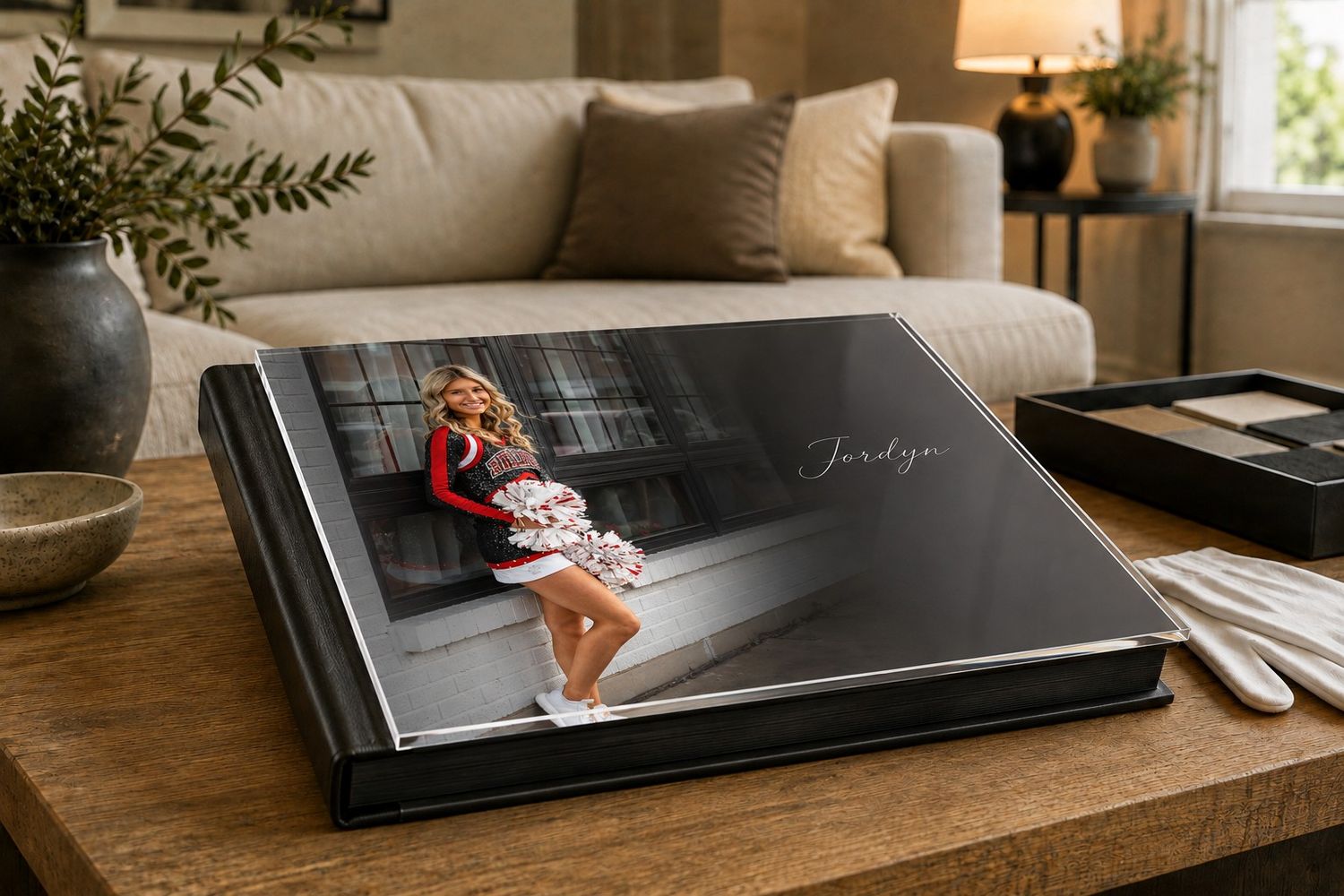 Elegant senior portrait photo book with a girl in floral dress displayed open on a wooden coffee table.