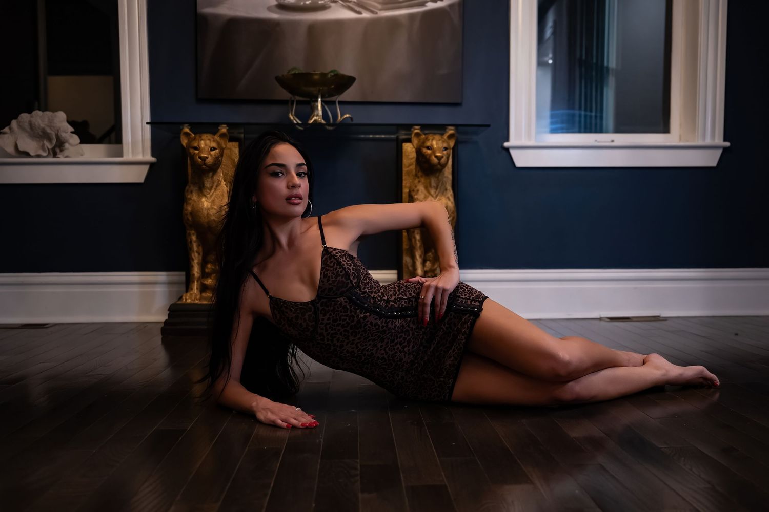 Dramatic boudoir photo in black lace against dark walls and window trim.