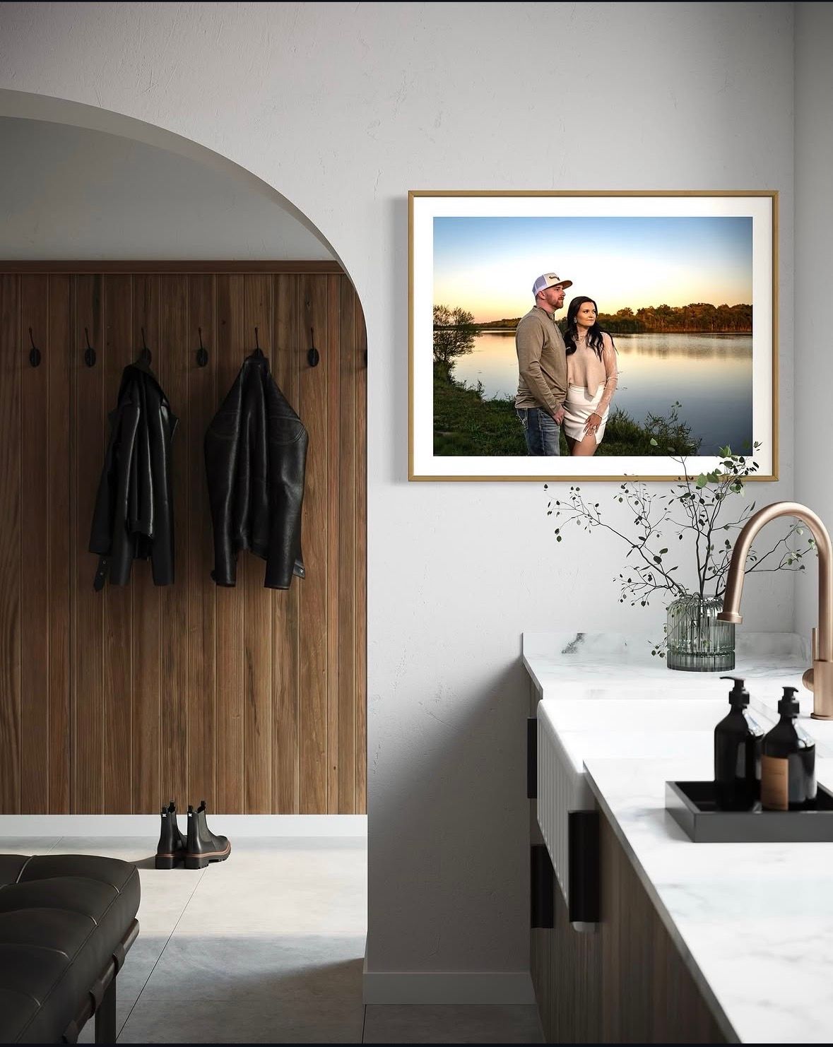 Framed photo of a couple by a lake at sunset displayed on a white wall above a modern kitchen counter.