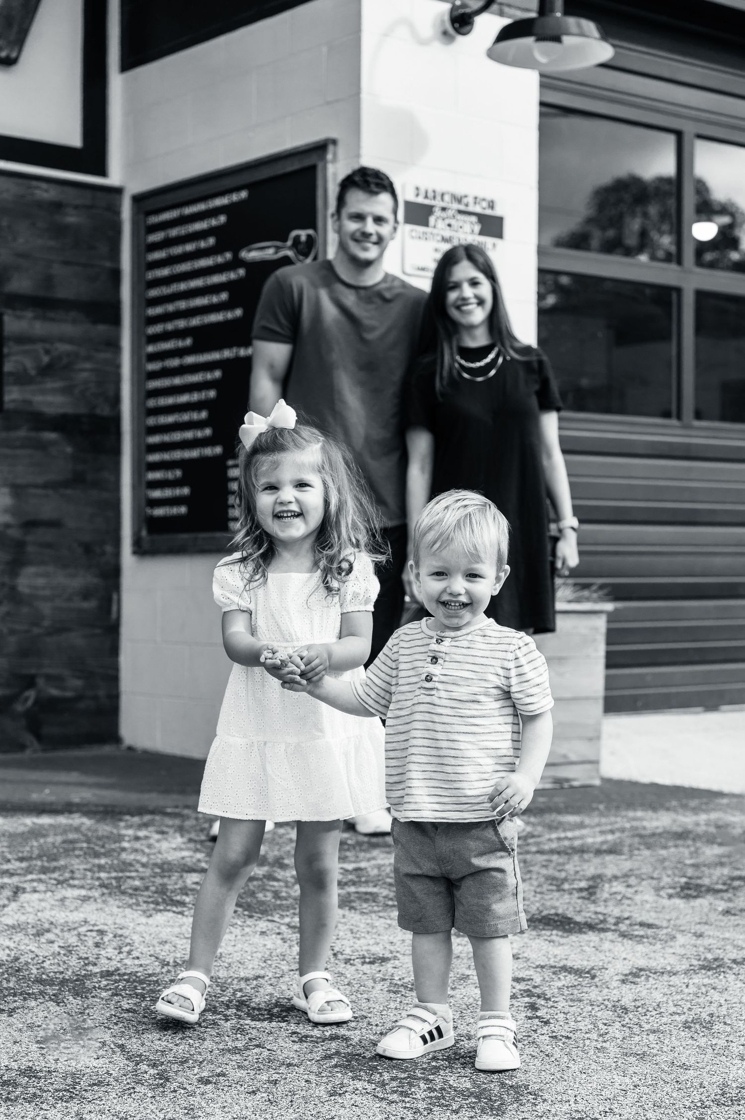 Black and white family portrait outside a storefront with signage.