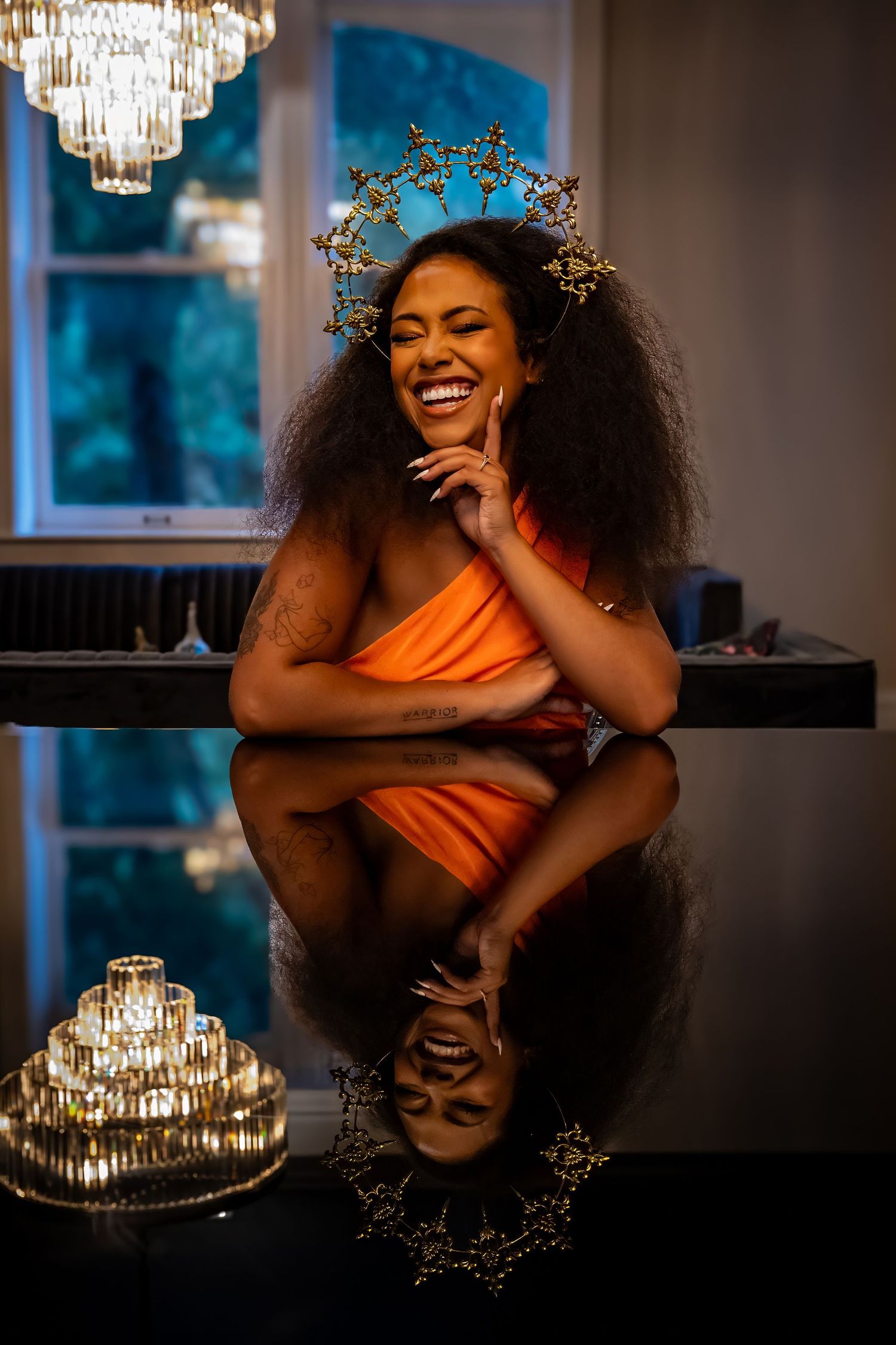 Artistic portrait with crystal chandelier and dramatic lighting creating reflective effects.