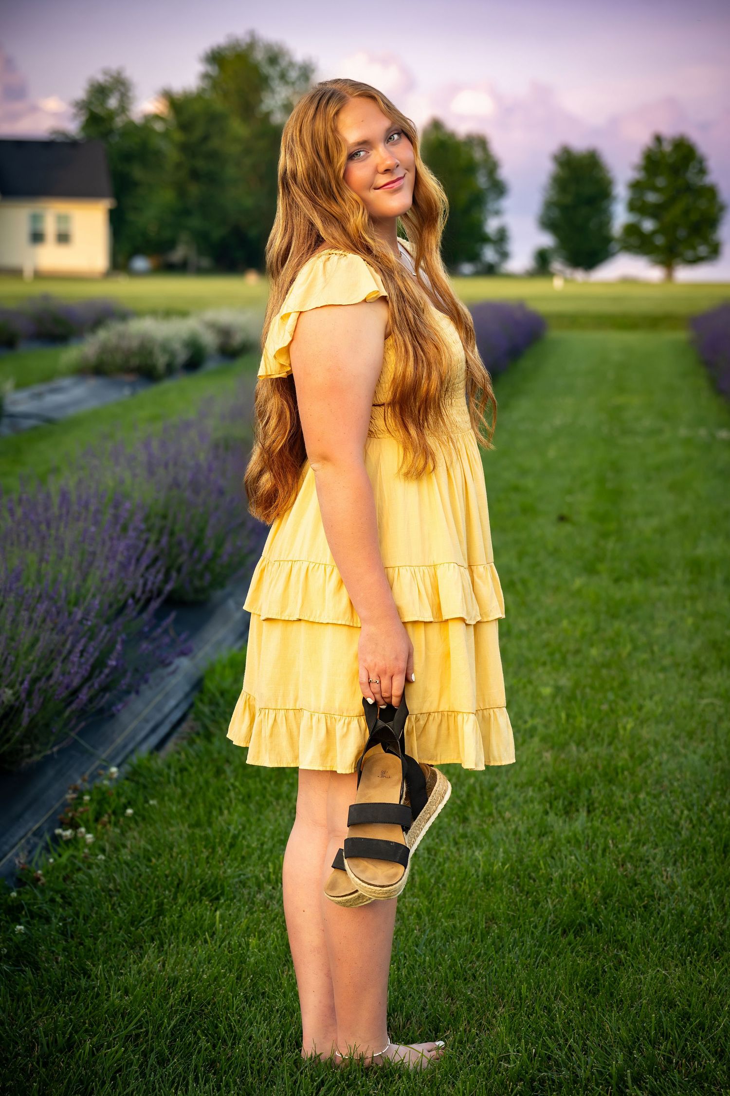 A yellow ruffled dress stands out against purple lavender blooms in a summer garden.