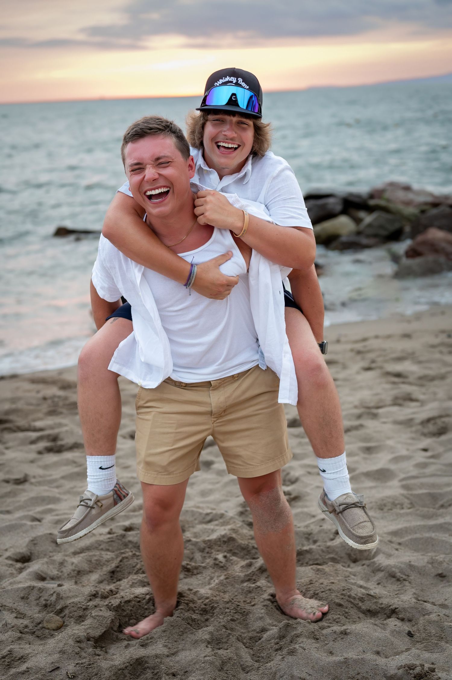 Playful piggyback ride on sandy beach during sunset.