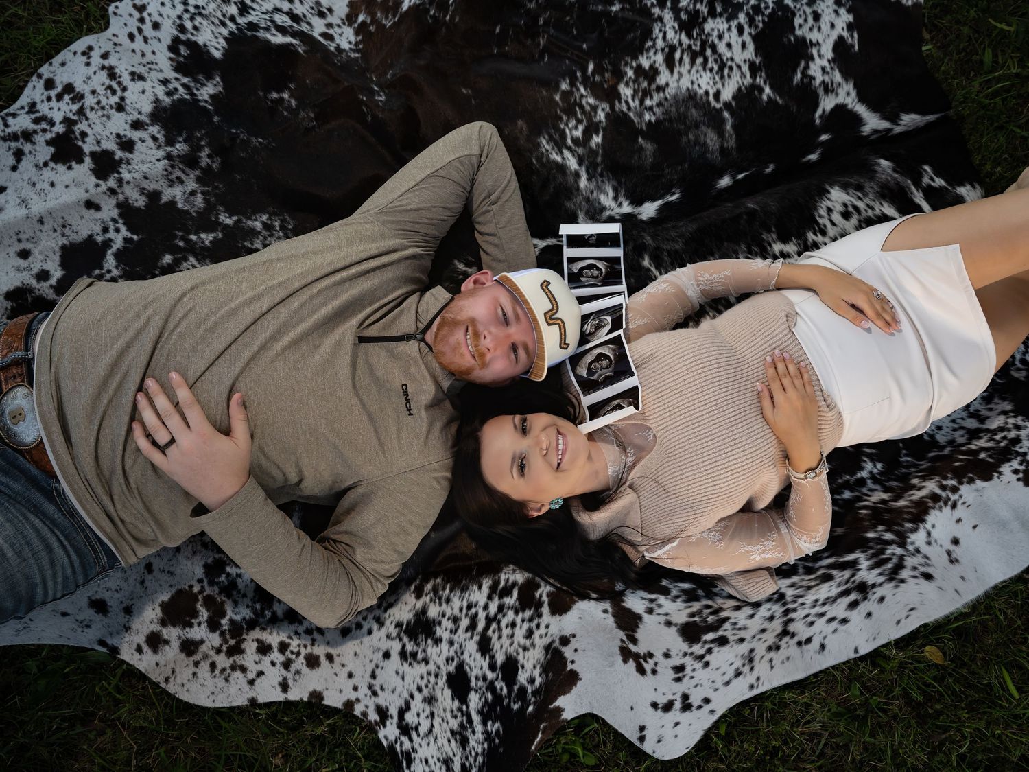 Creative maternity photoshoot on textured ground with natural outdoor lighting.