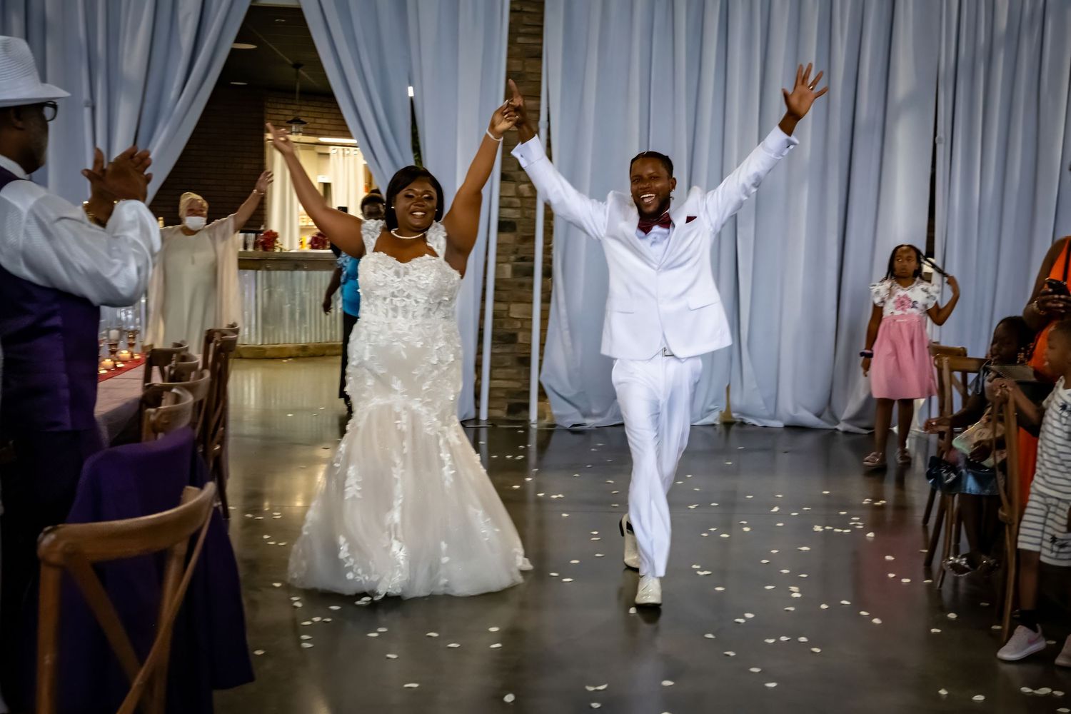Wedding reception dance floor with white curtains and guests dancing in formal attire.