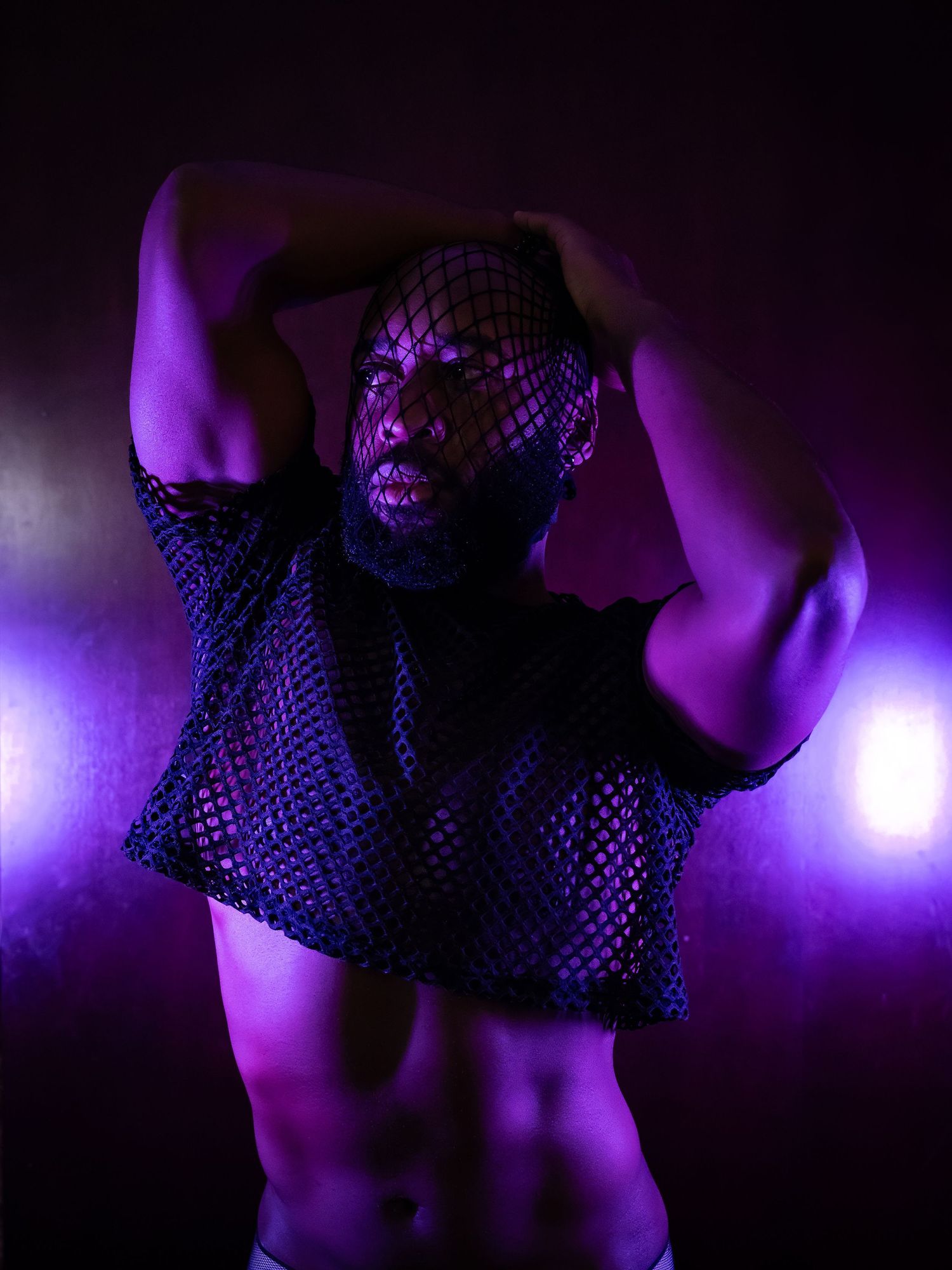 Abstract photo with mesh fabric details illuminated by purple lighting in dark environment.