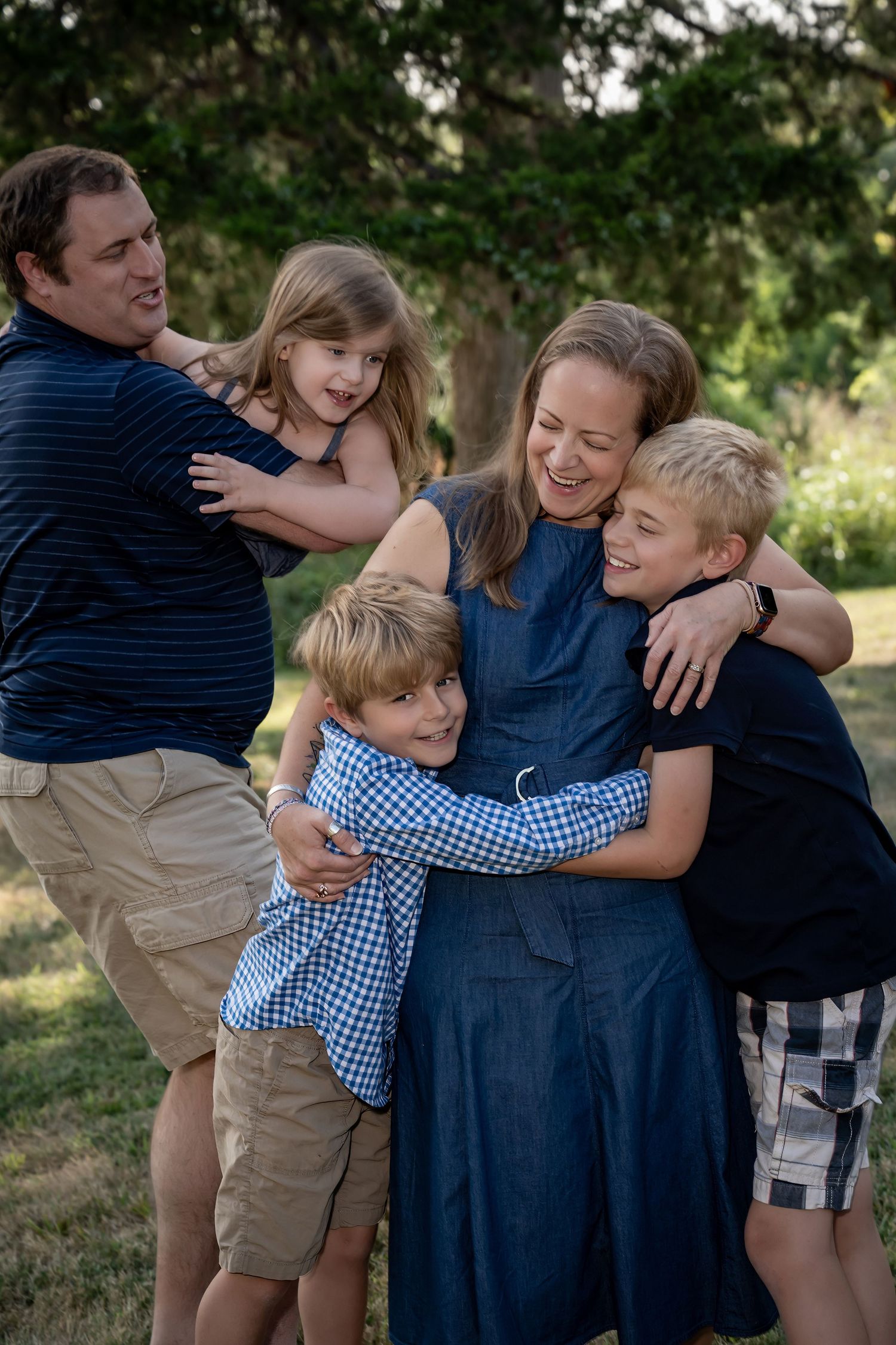 Family sharing warm embrace outdoors in summer garden setting.