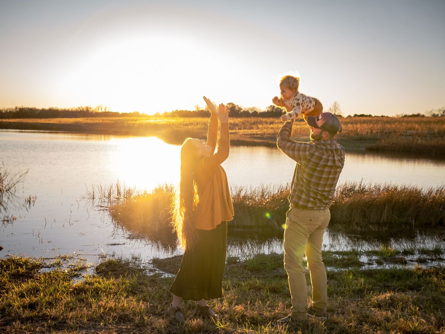 A sunset photo session by a serene lake with golden light reflecting off the water.