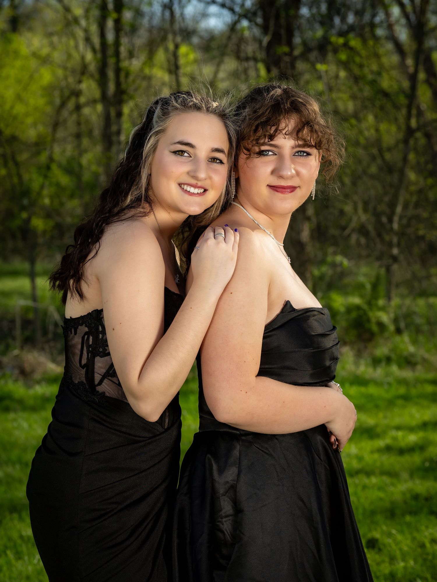 Two people in black formal wear embracing outdoors in a spring garden setting.