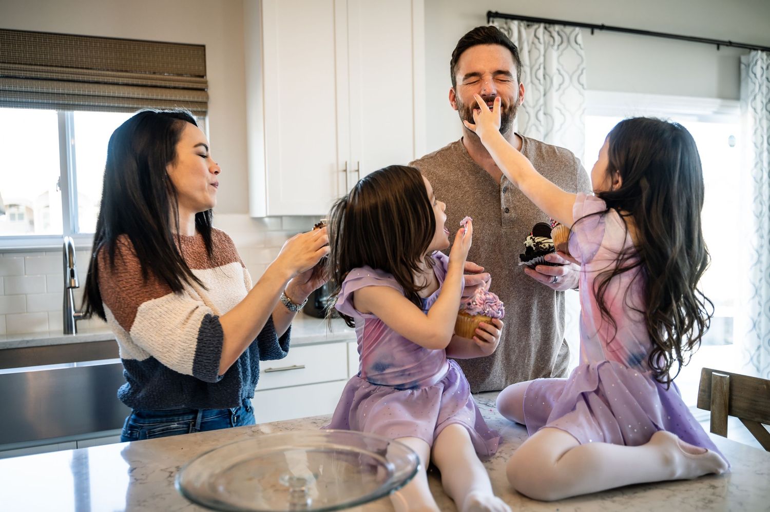 Happy family moment sharing desserts and smiles in a bright room.