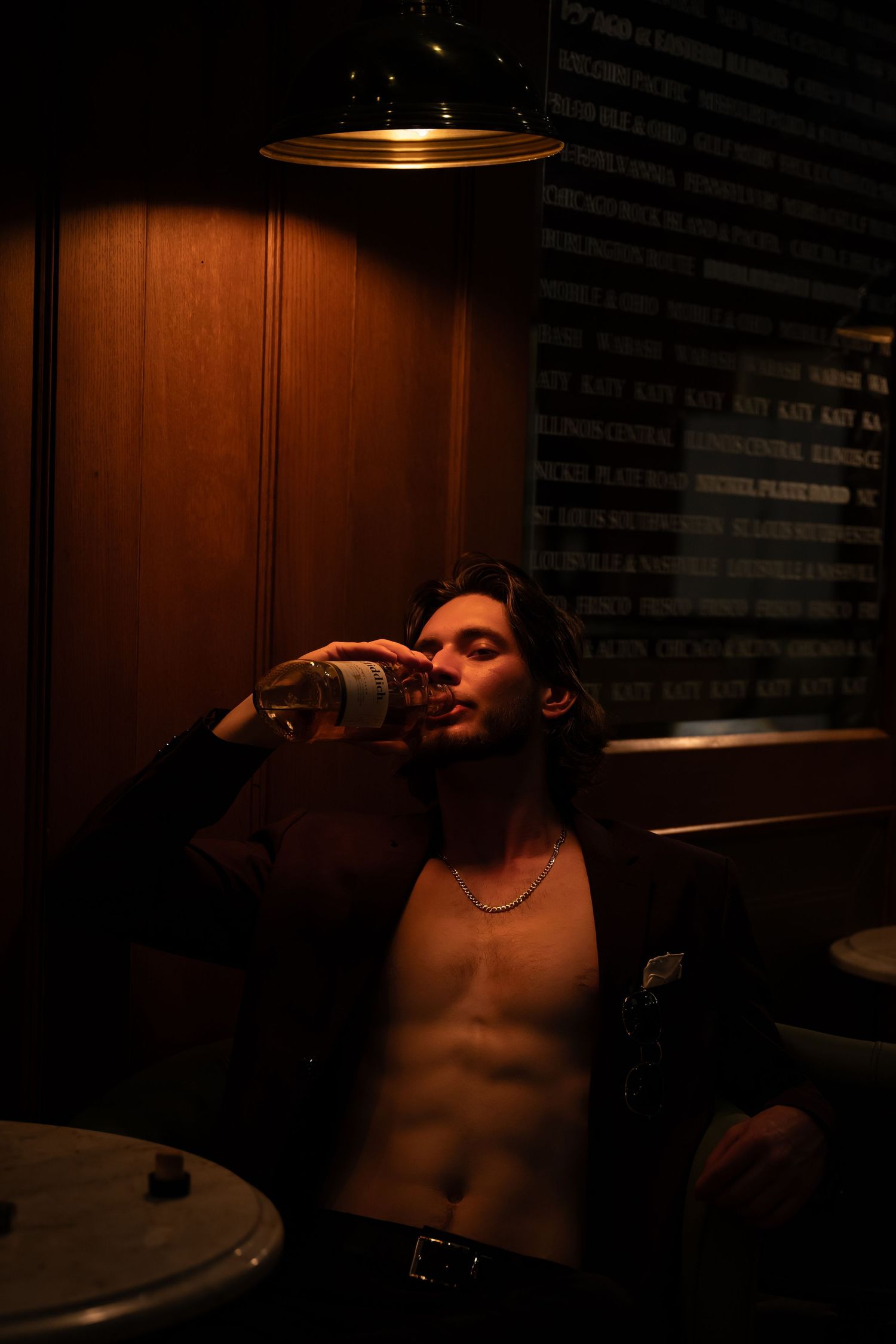 Person drinking from bottle in dramatic low-key lighting against dark background.