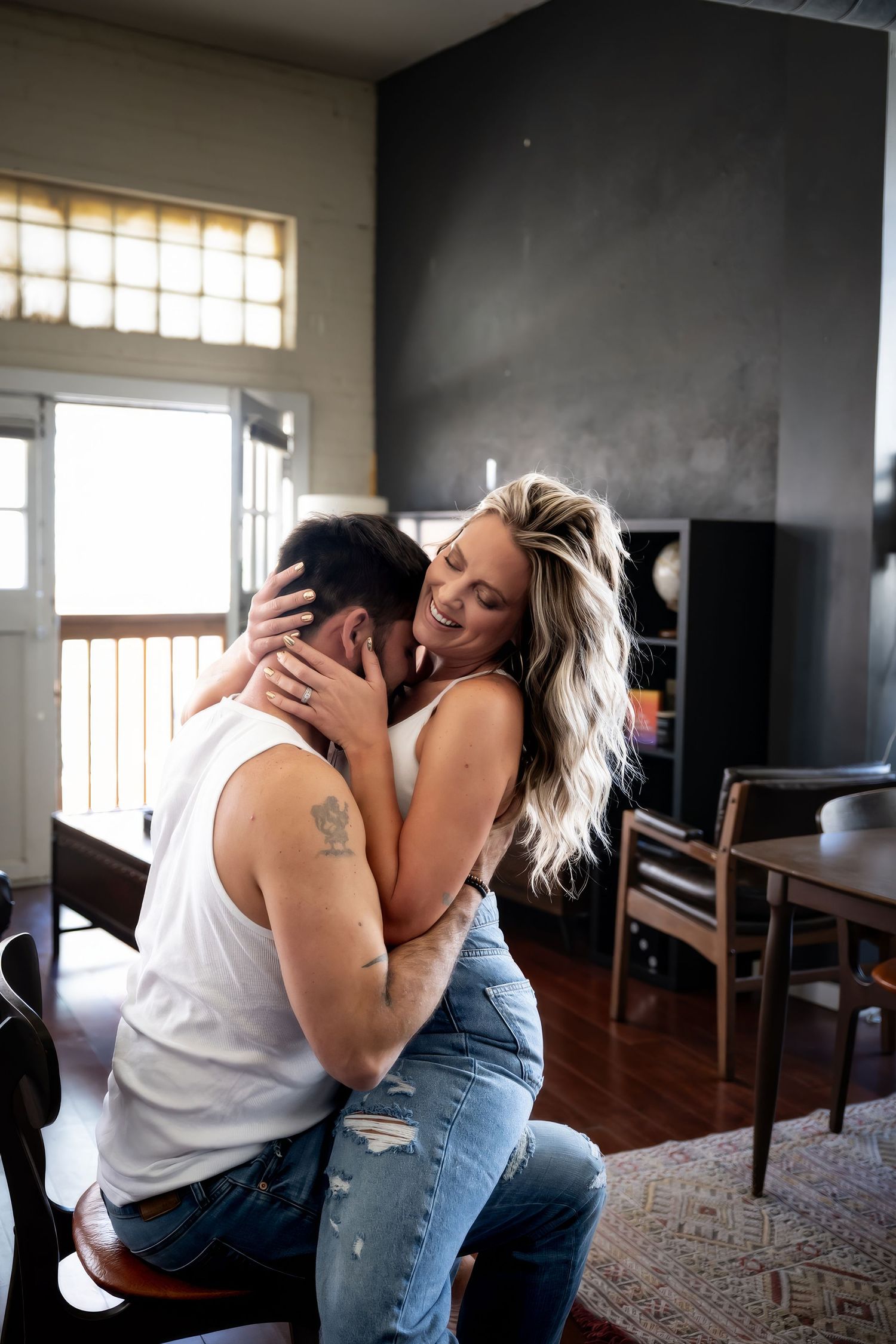 Intimate couple sharing tender moment in living room with sunlight streaming through window.