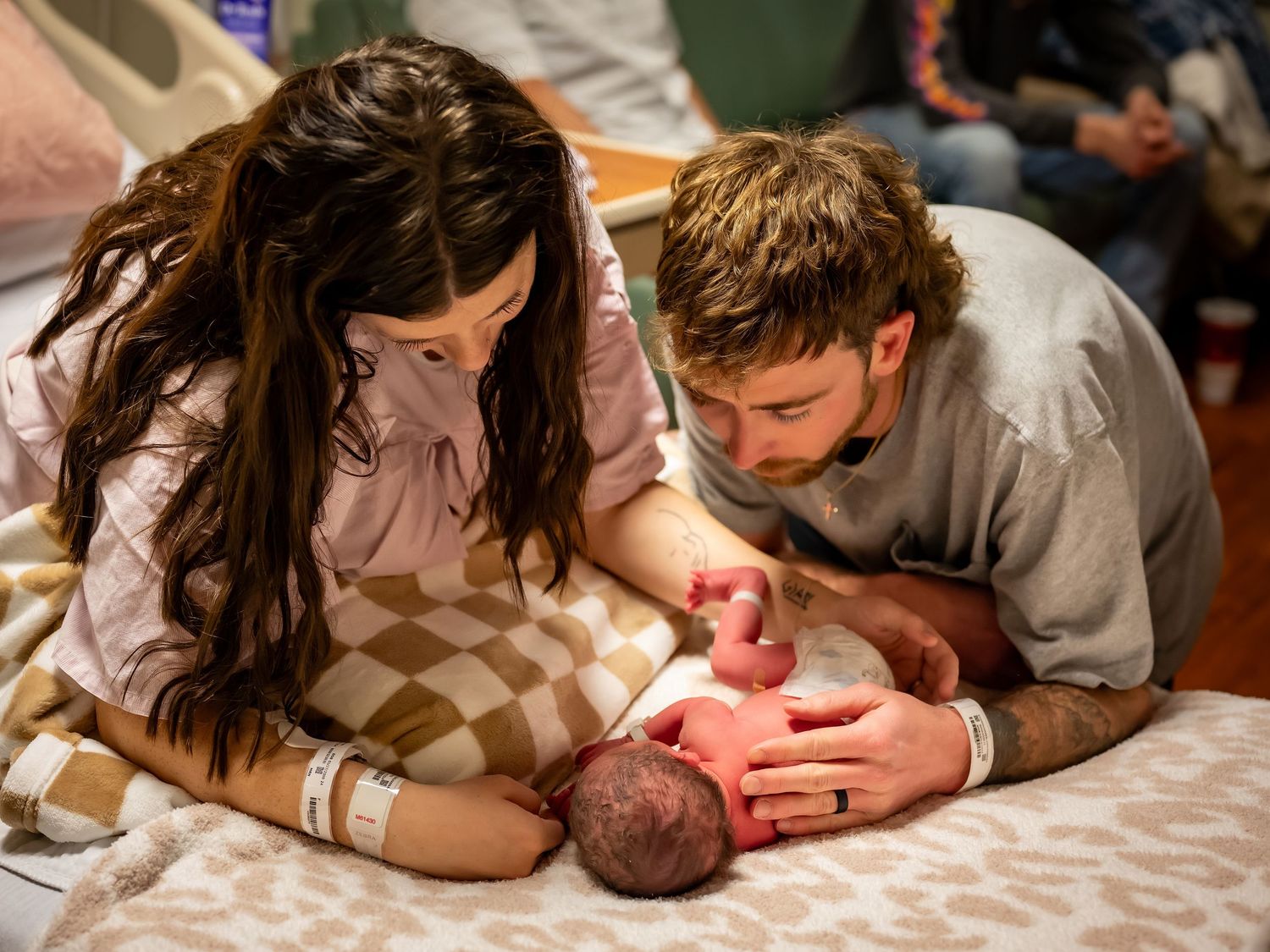 Intimate family moment with newborn baby on soft bedding.