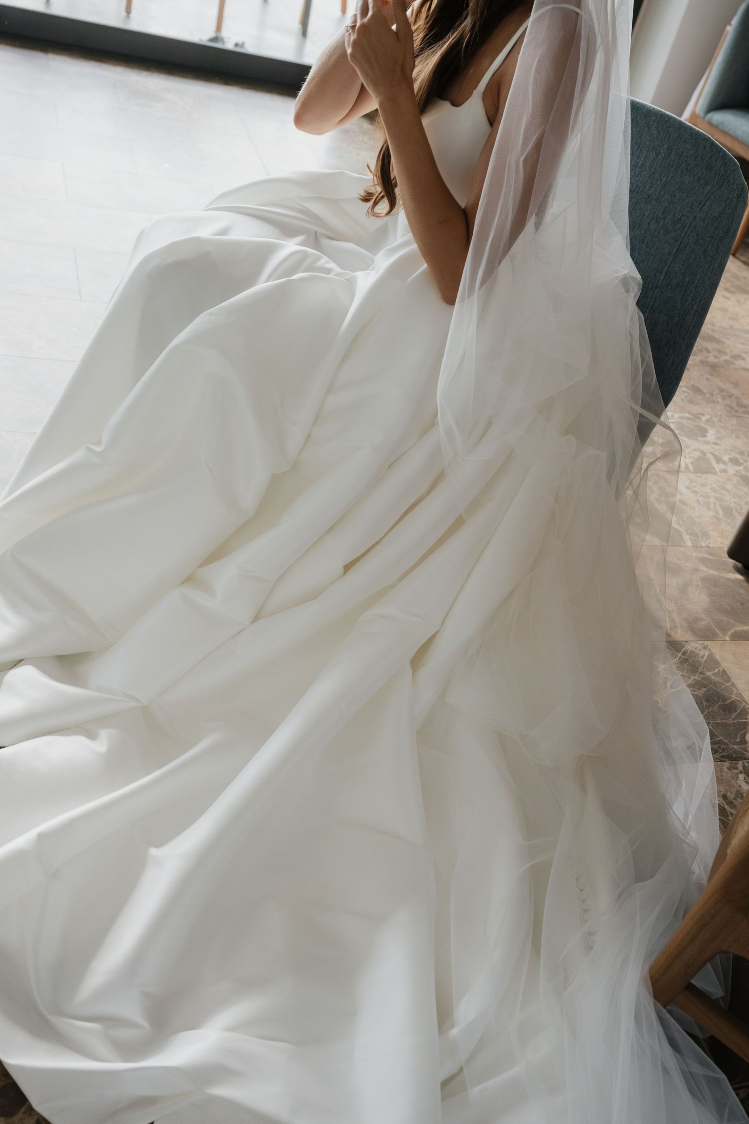 Close-up details of a flowing white wedding dress with layered tulle and fabric.