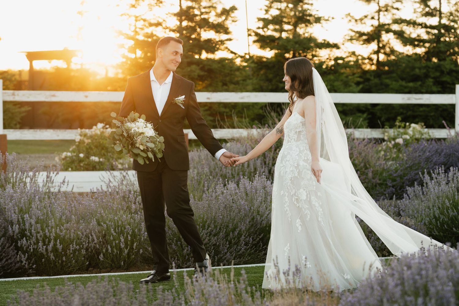 A joyful wedding couple dancing together among lavender plants at golden hour.
