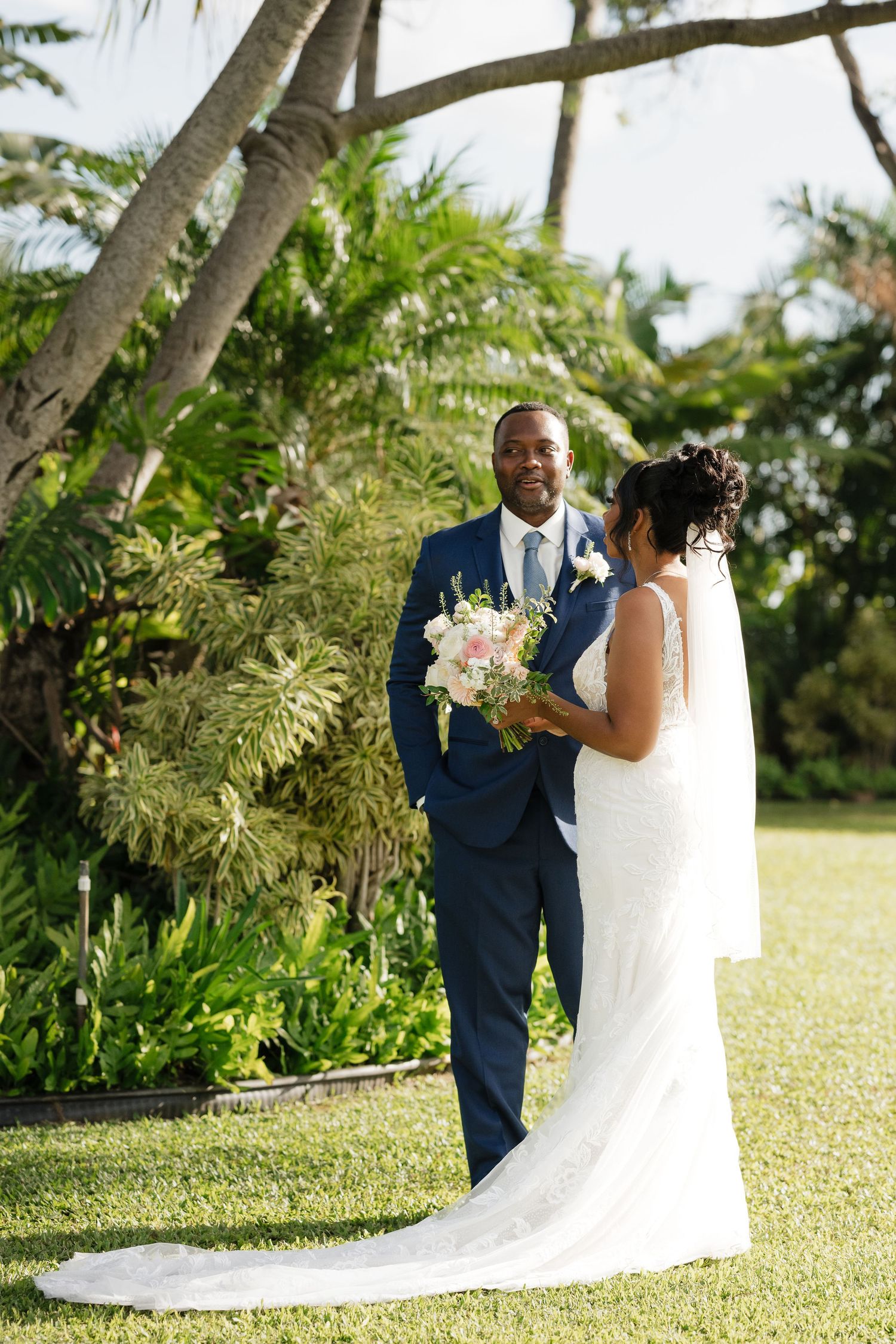 Wedding couple photographed in a lush tropical garden setting with palm trees.