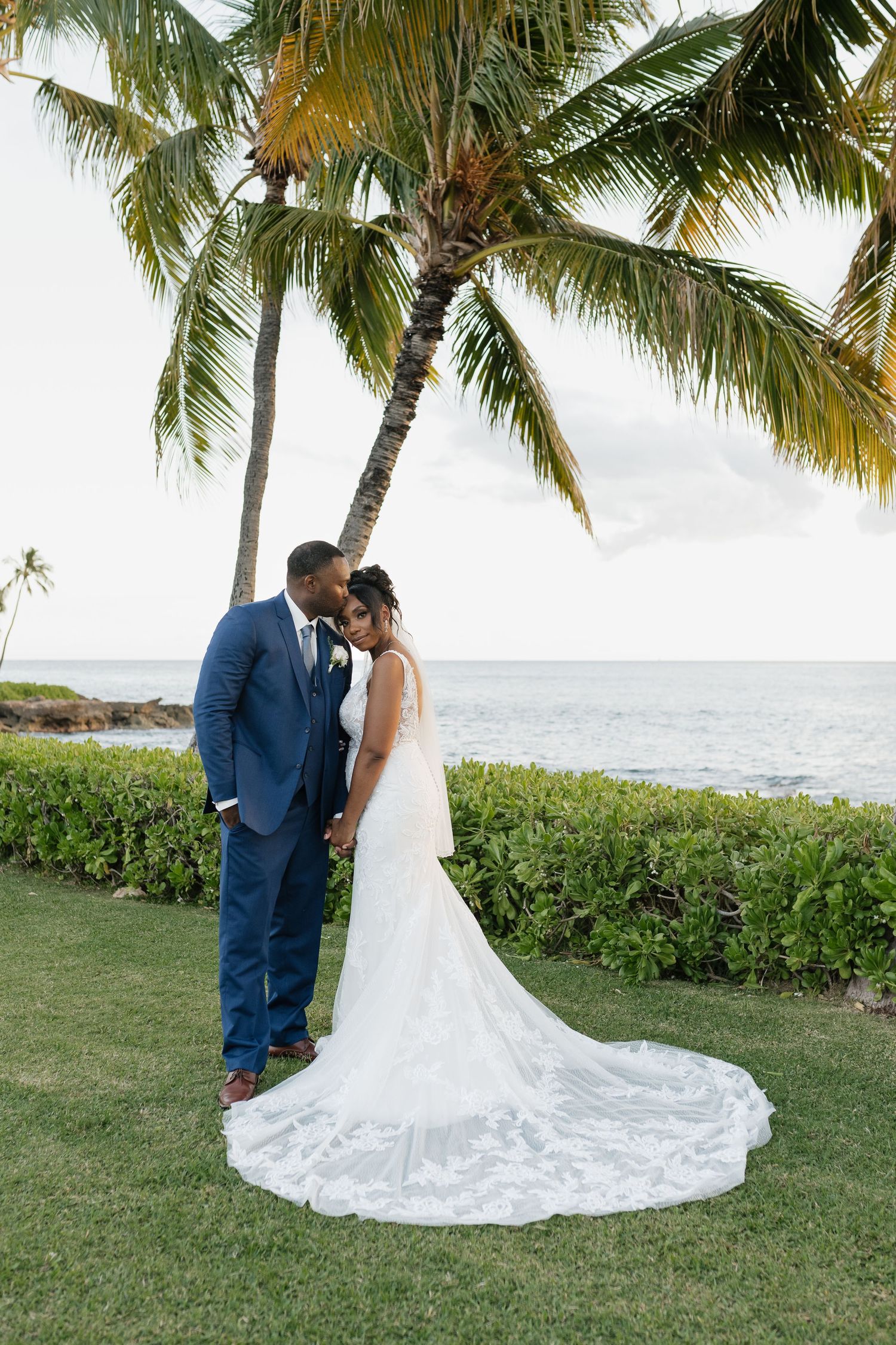 Elegant wedding portraits under swaying palm trees by the ocean.