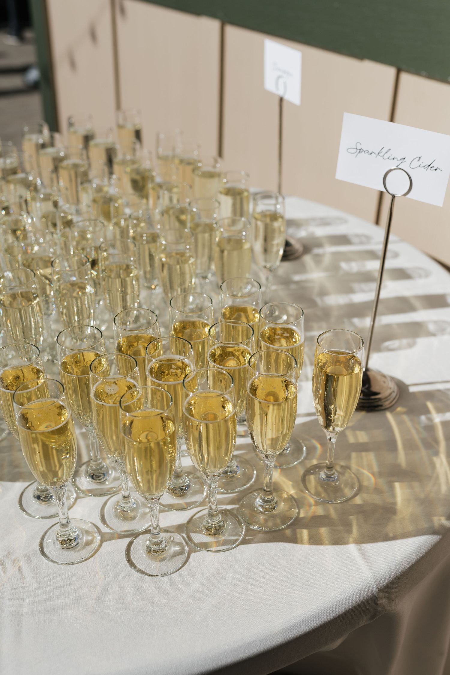 Rows of champagne flutes filled with bubbly on an elegant white table setting.