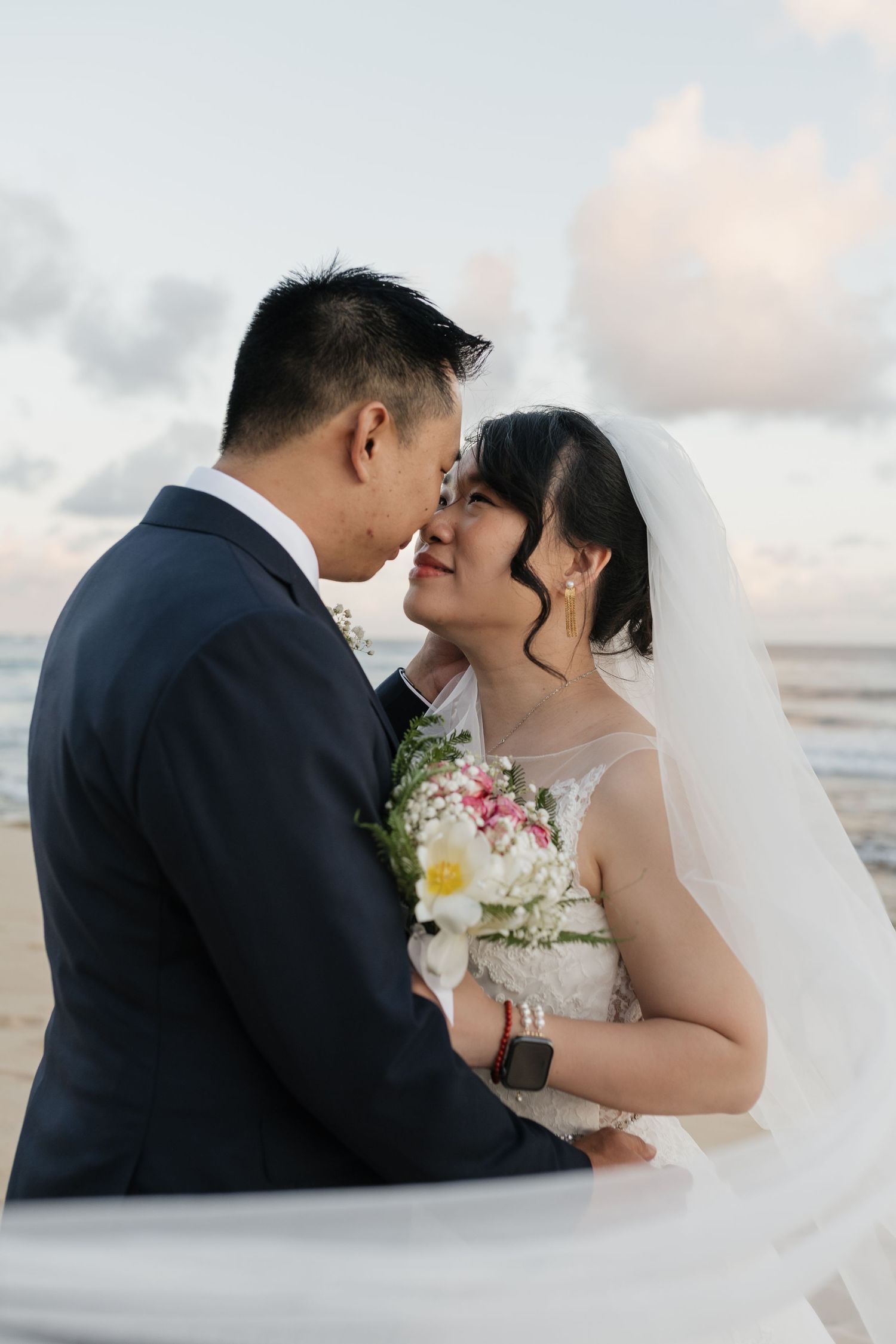 Intimate beach wedding portraits with soft sunset lighting and ocean backdrop.