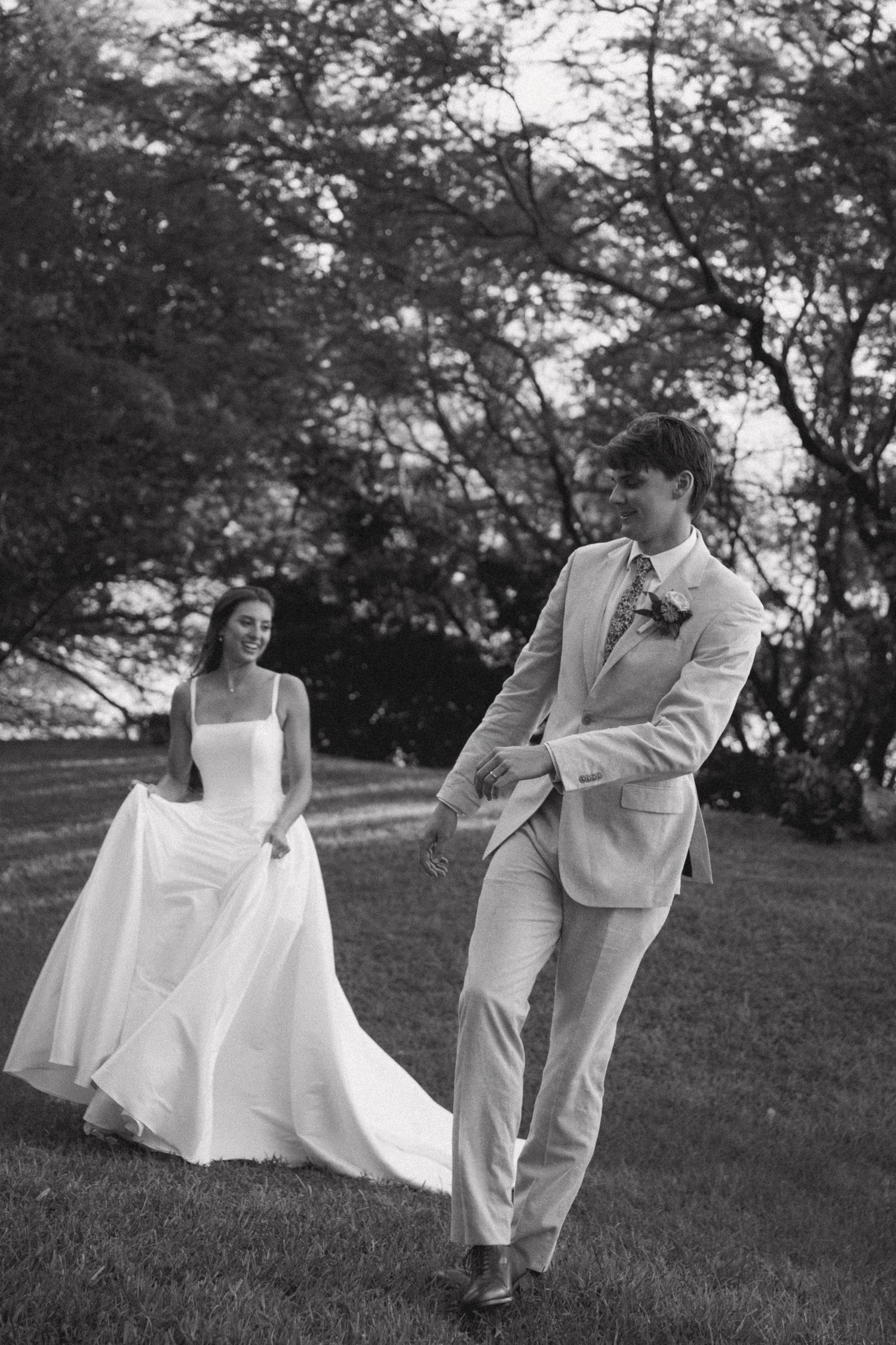 Black and white wedding portraits on a grassy hillside with flowing dress movement.