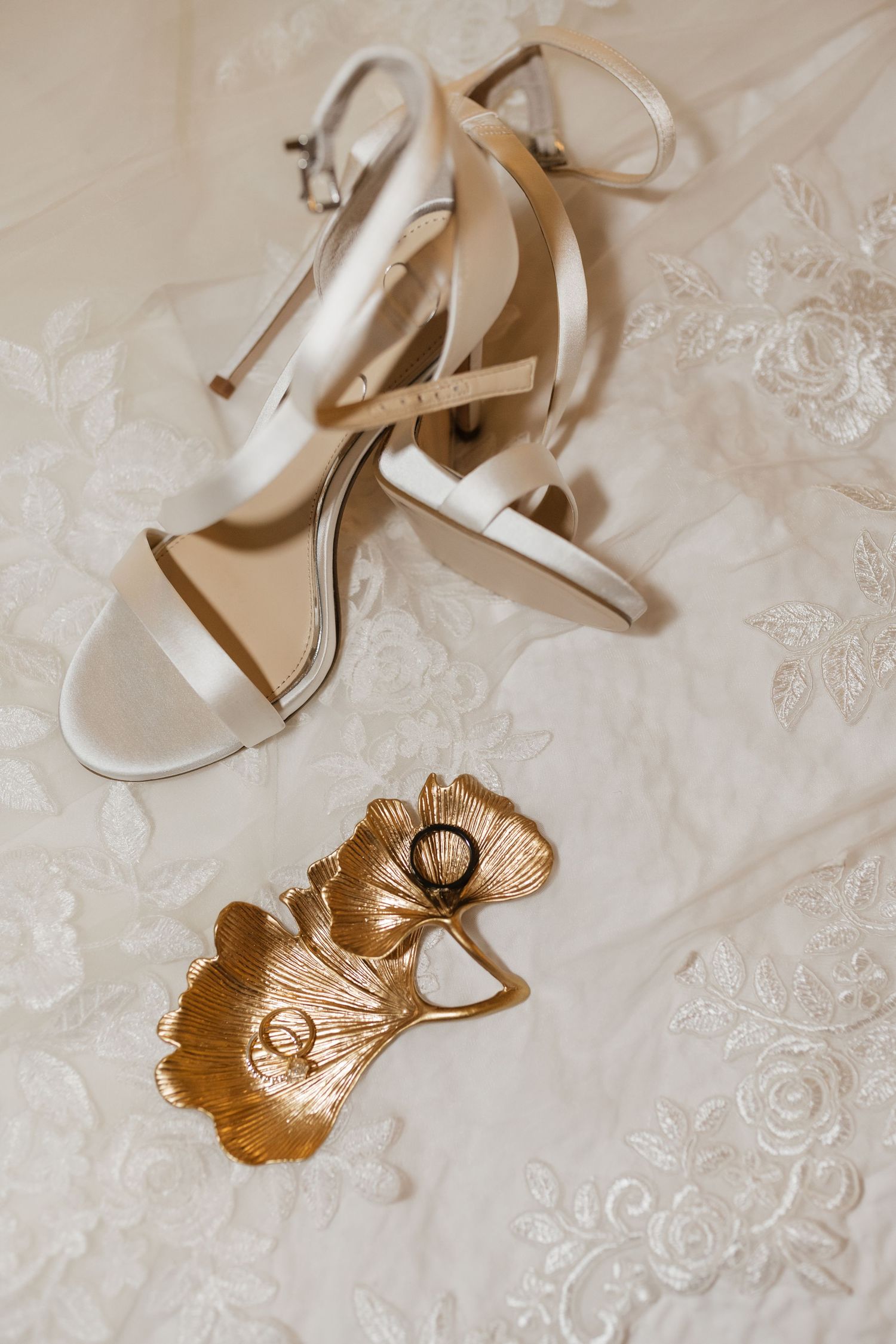Elegant wedding accessories including beige heels and gold leaf decorations.