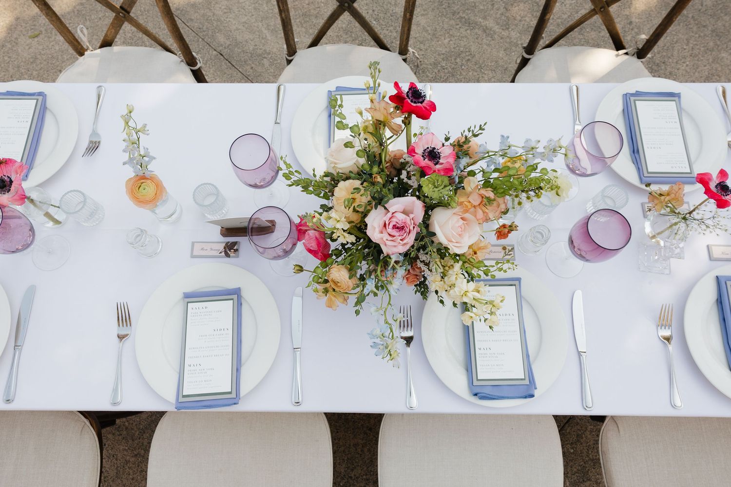Elegant wedding reception table settings with white linens, floral centerpieces, and place settings in soft pastel colors.