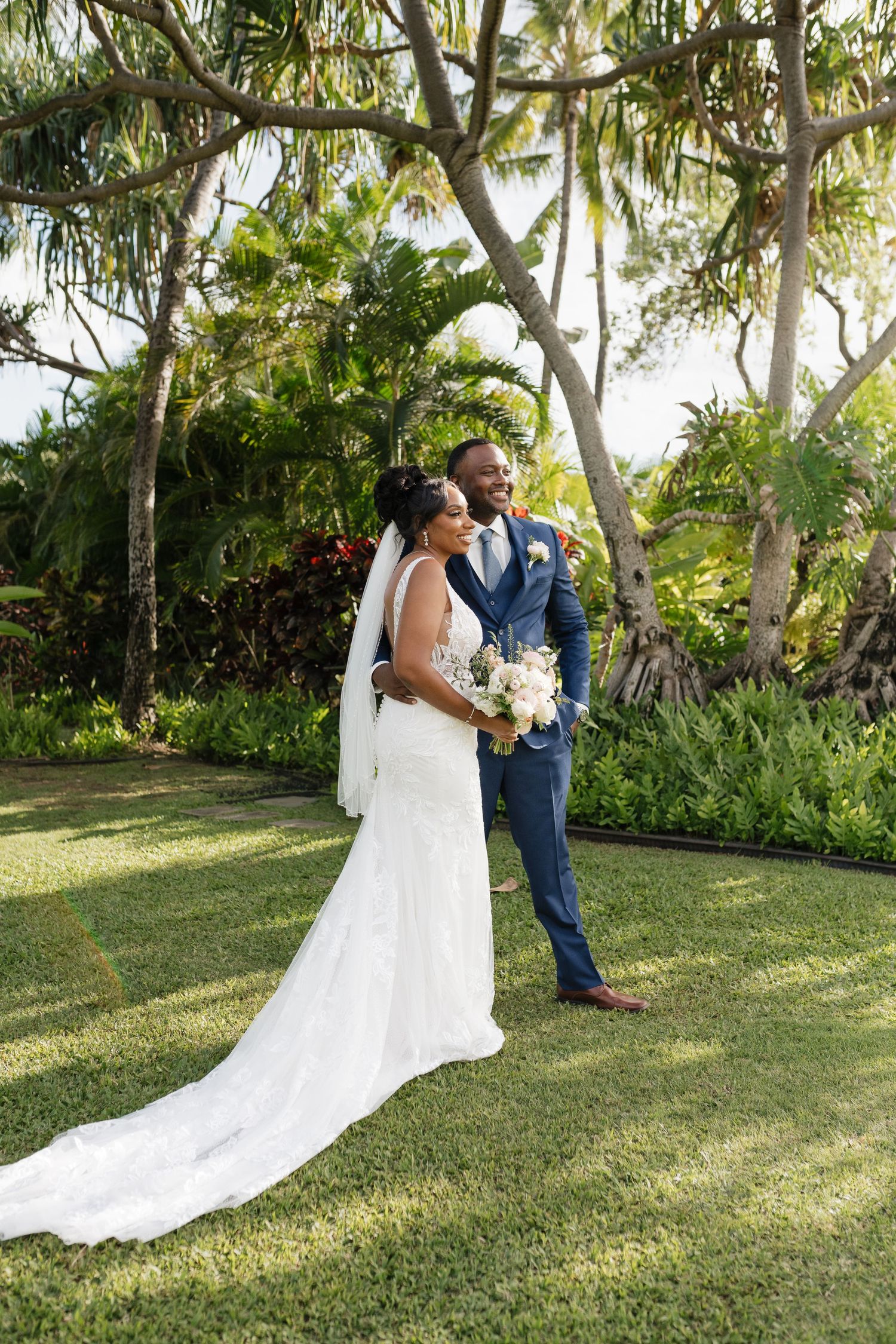 Wedding couple walks through a lush tropical garden setting during their photoshoot.