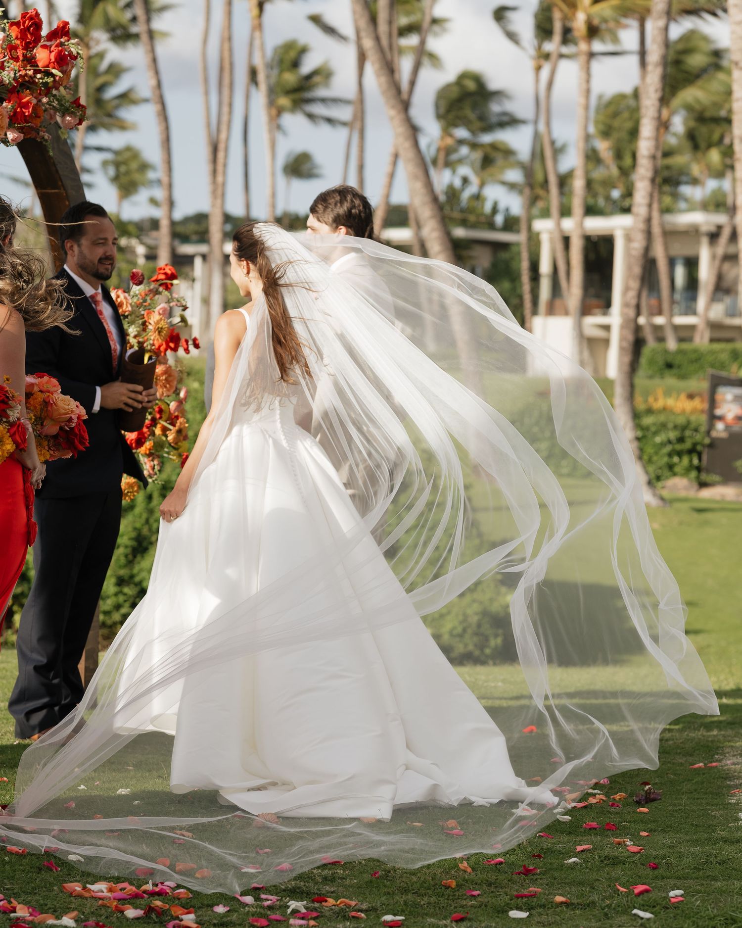Flowing white wedding veil billowing in the breeze at a tropical palm tree ceremony.