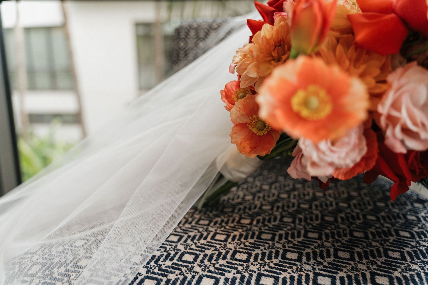 Coral-colored flowers and white fabric create a romantic wedding detail arrangement.