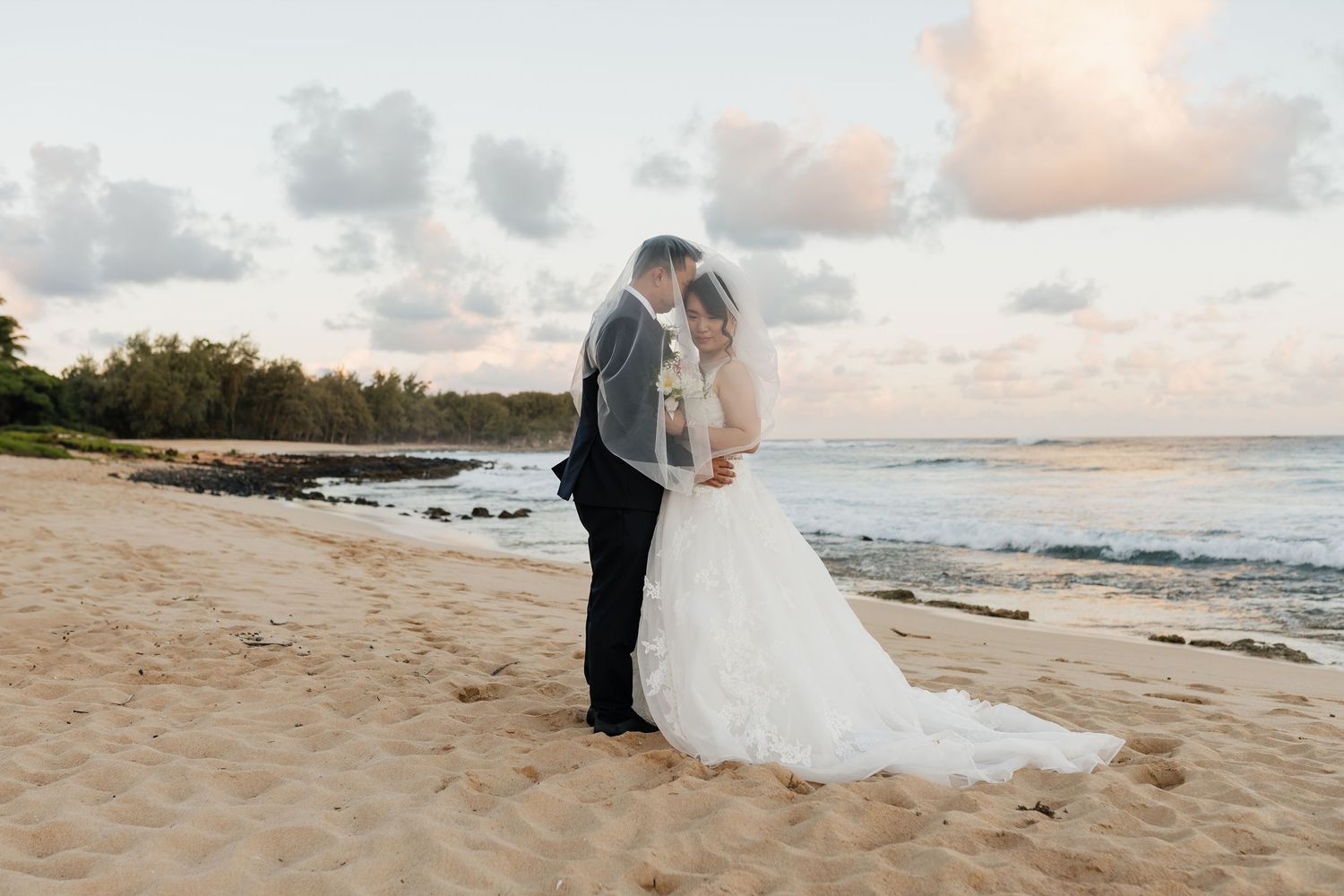 Romantic beach wedding photography session with gentle waves in the background.