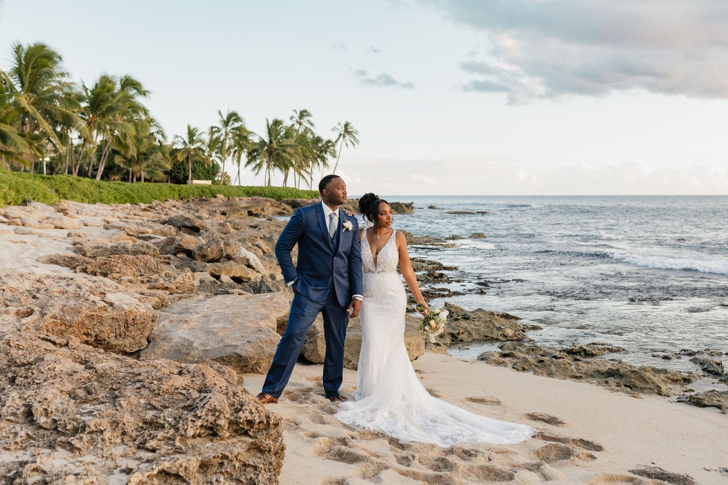 A romantic beachside moment captured against a backdrop of palm trees and ocean waves.