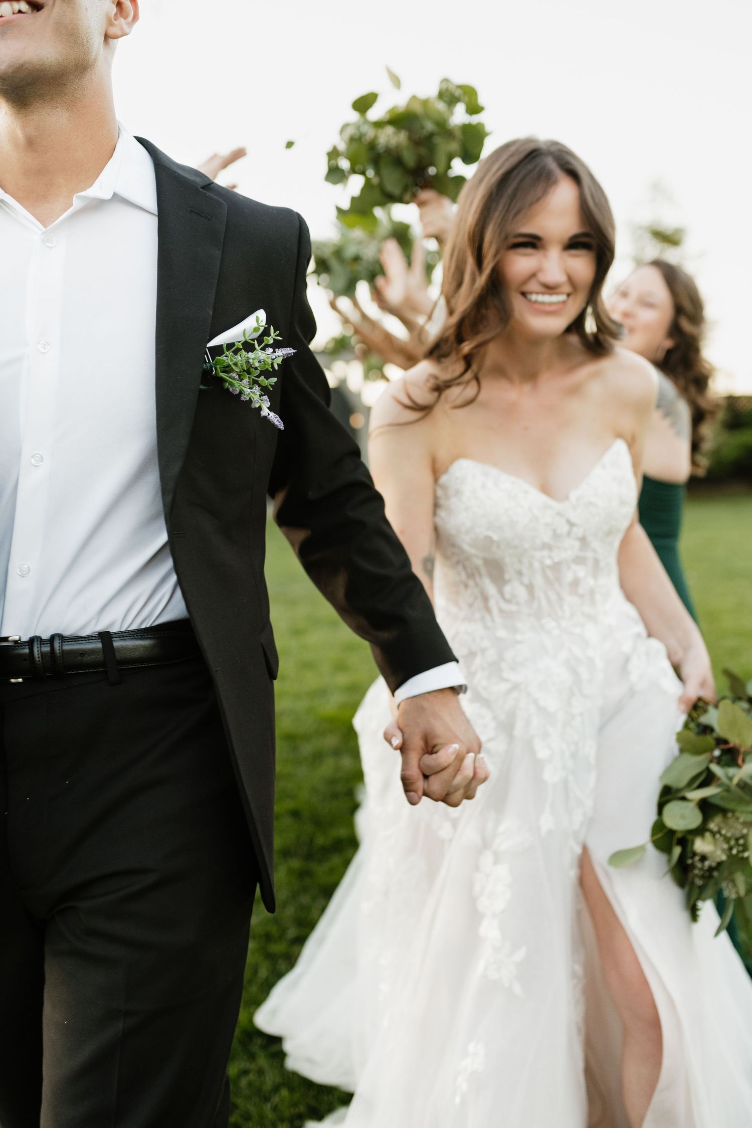 A candid wedding moment showing a couple holding hands and smiling in an outdoor garden setting.