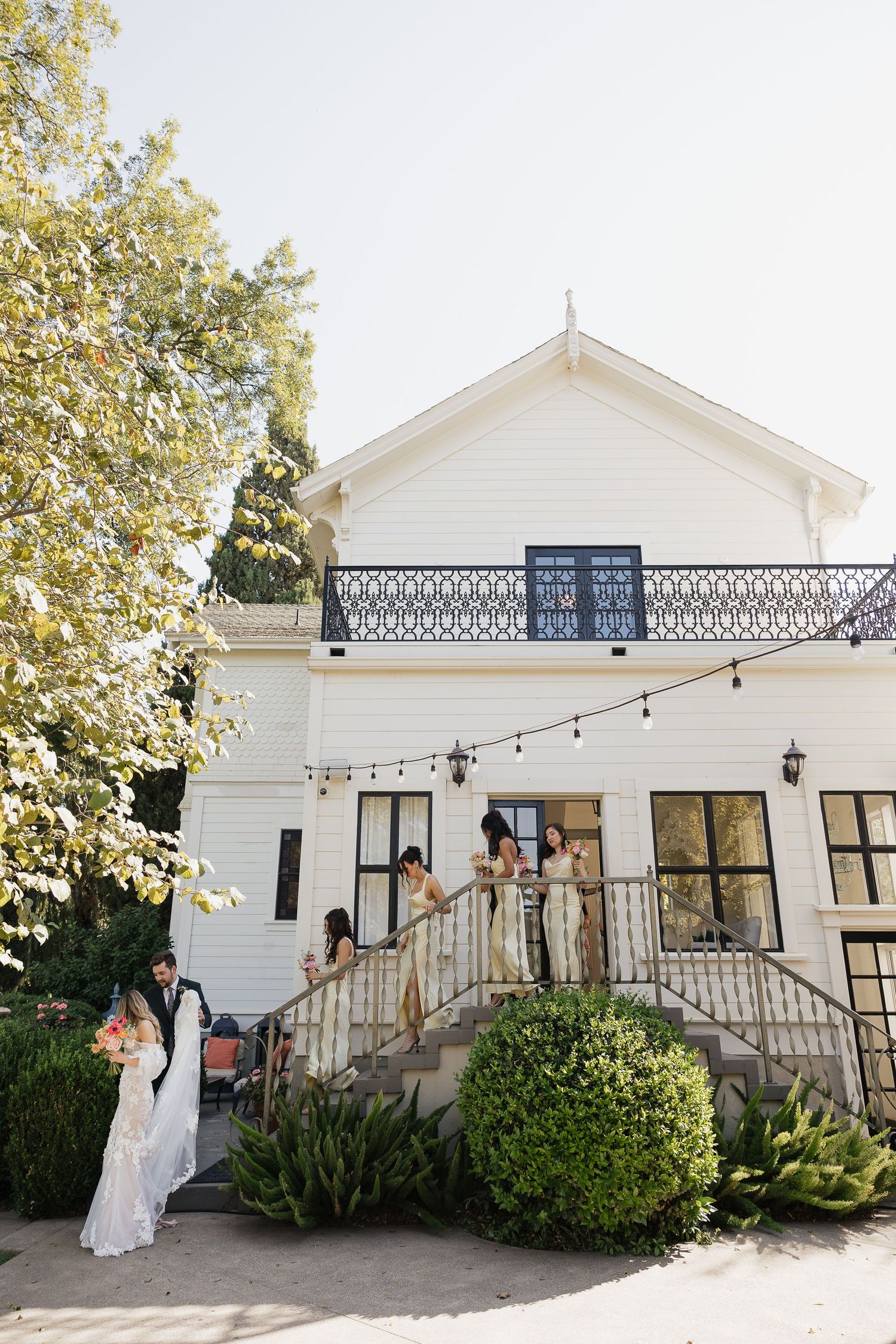 White farmhouse style venue with string lights and decorative railing on the front porch.