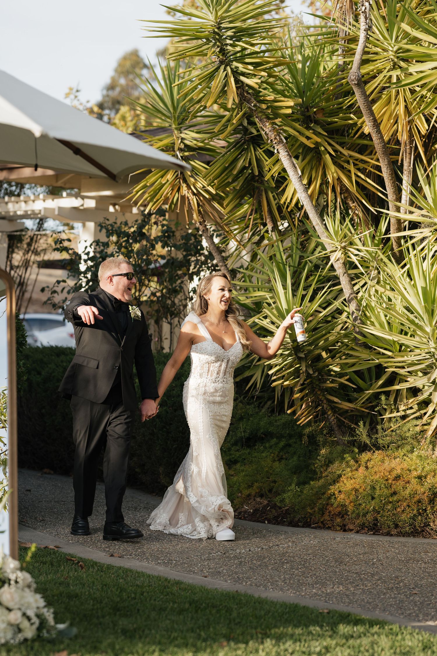 Wedding couple dancing on a gravel path surrounded by tropical plants.