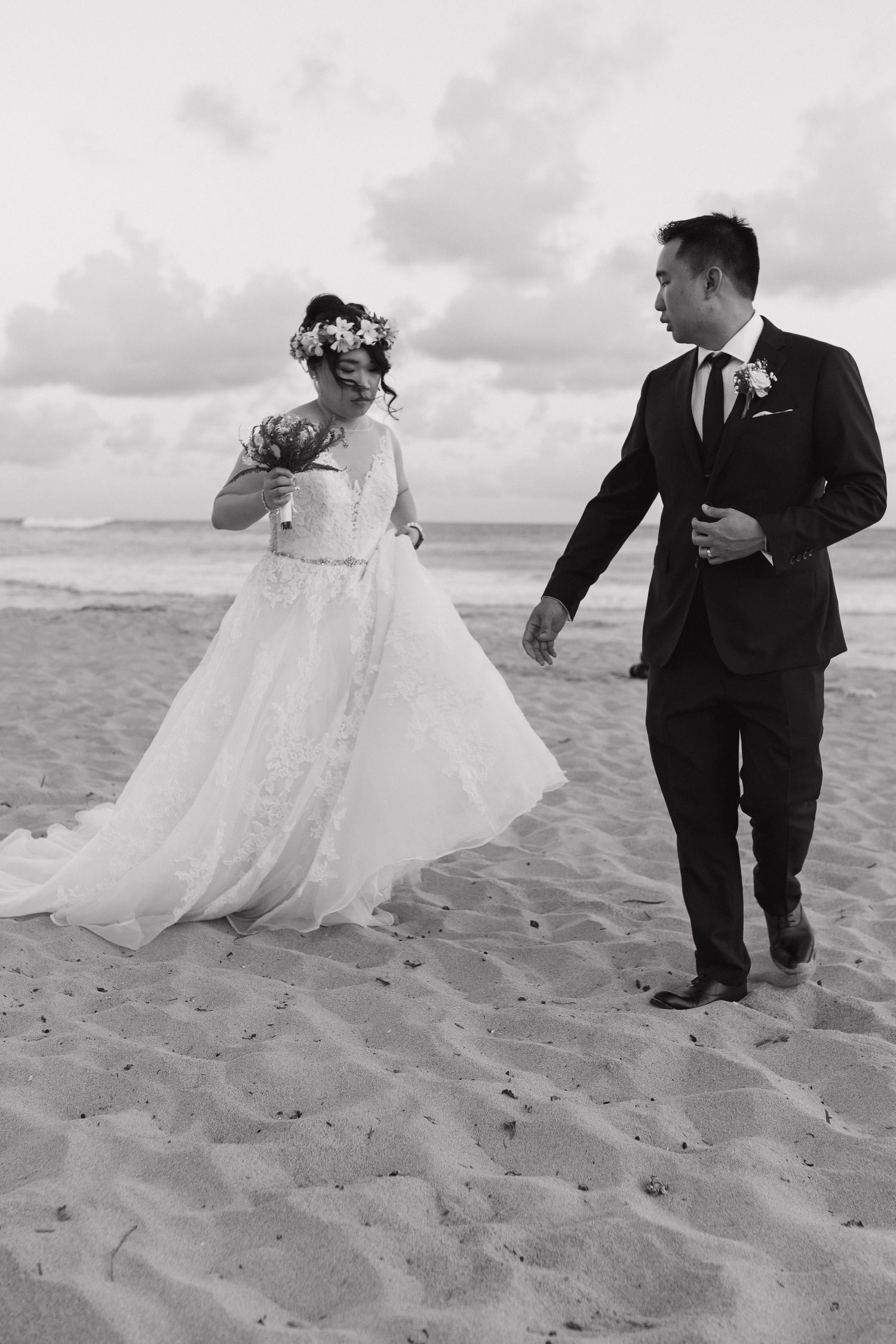 Black and white photo of couple dancing playfully on beach sand.